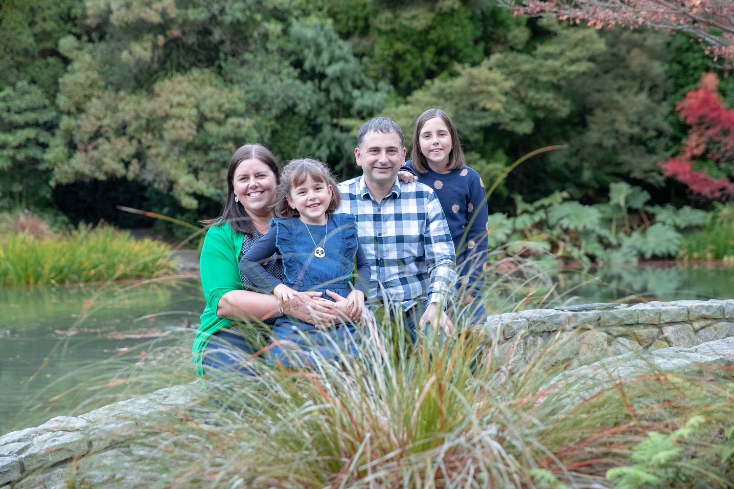 Family group photo session in a scenic park setting with natural landscaping.