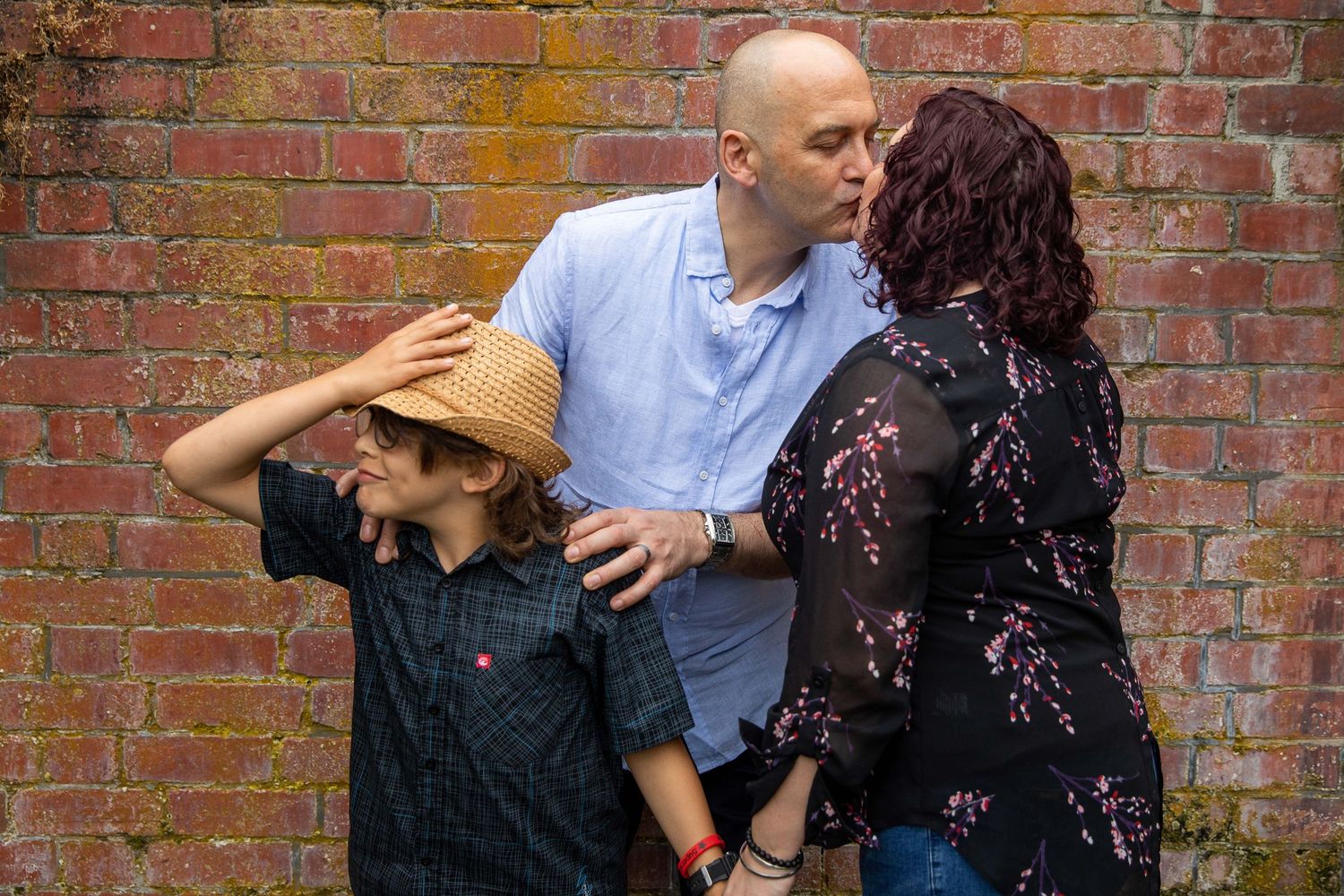 Candid moment of group interaction against red brick wall backdrop.