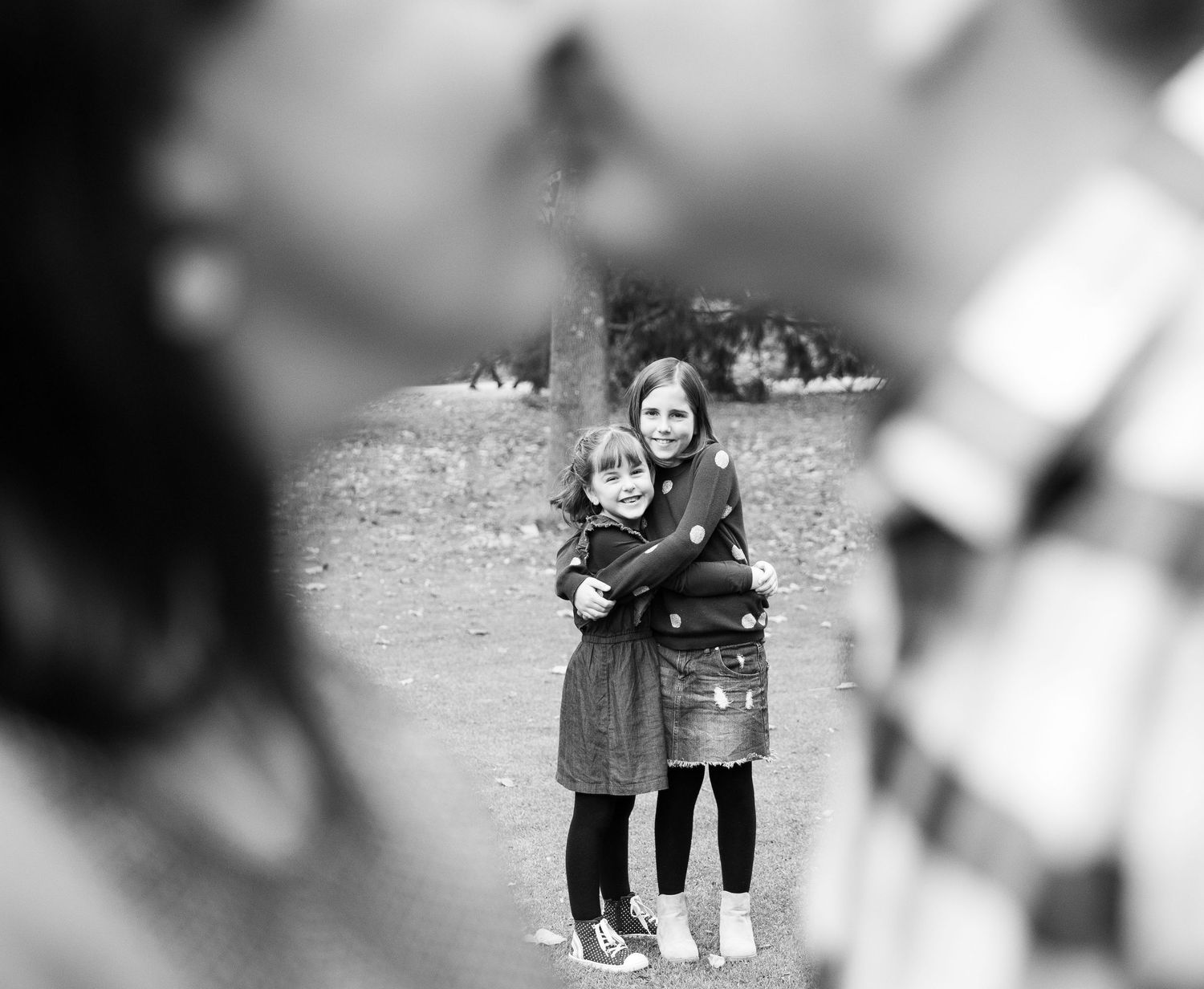 A black and white vintage photograph showing two people embracing outdoors on a grassy field.