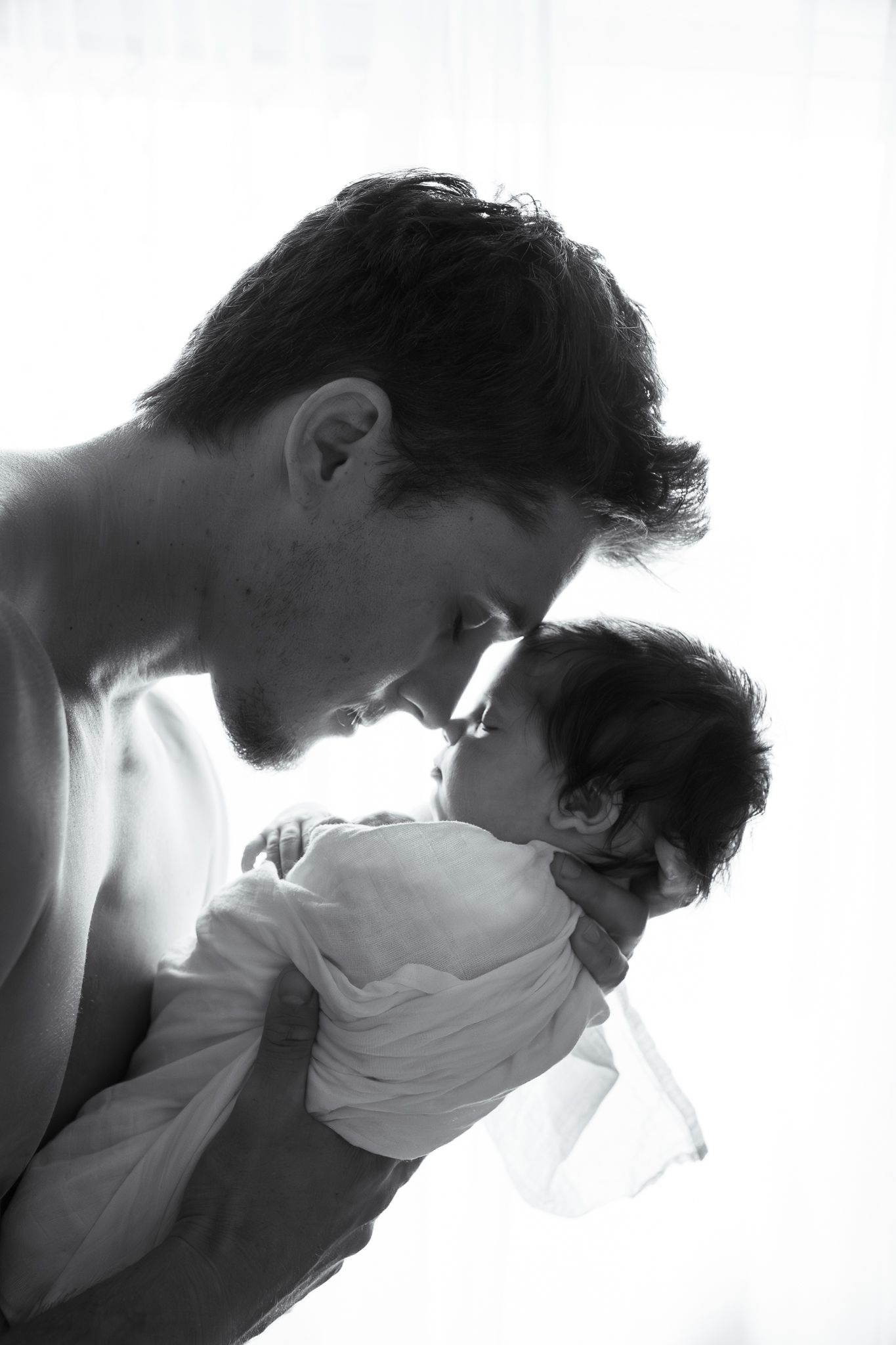 Dad holding newborn nose to nose black and white natural light in home session - Photos by Bailey Rose Gold Coast