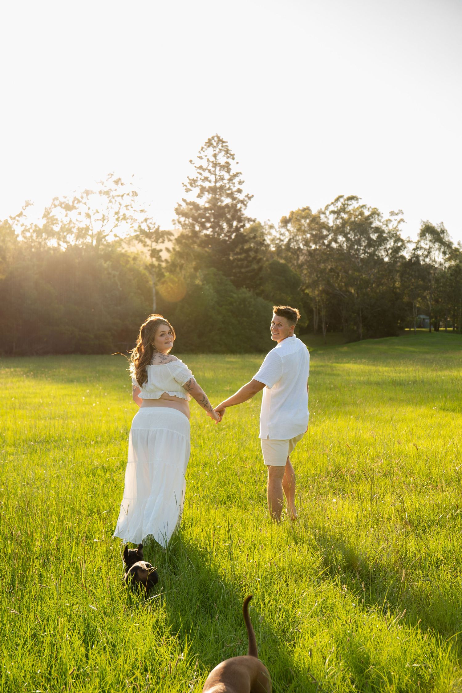 Couple holding hands walking away Maternity golden hour in open field - Photos by Bailey Rose Gold Coast