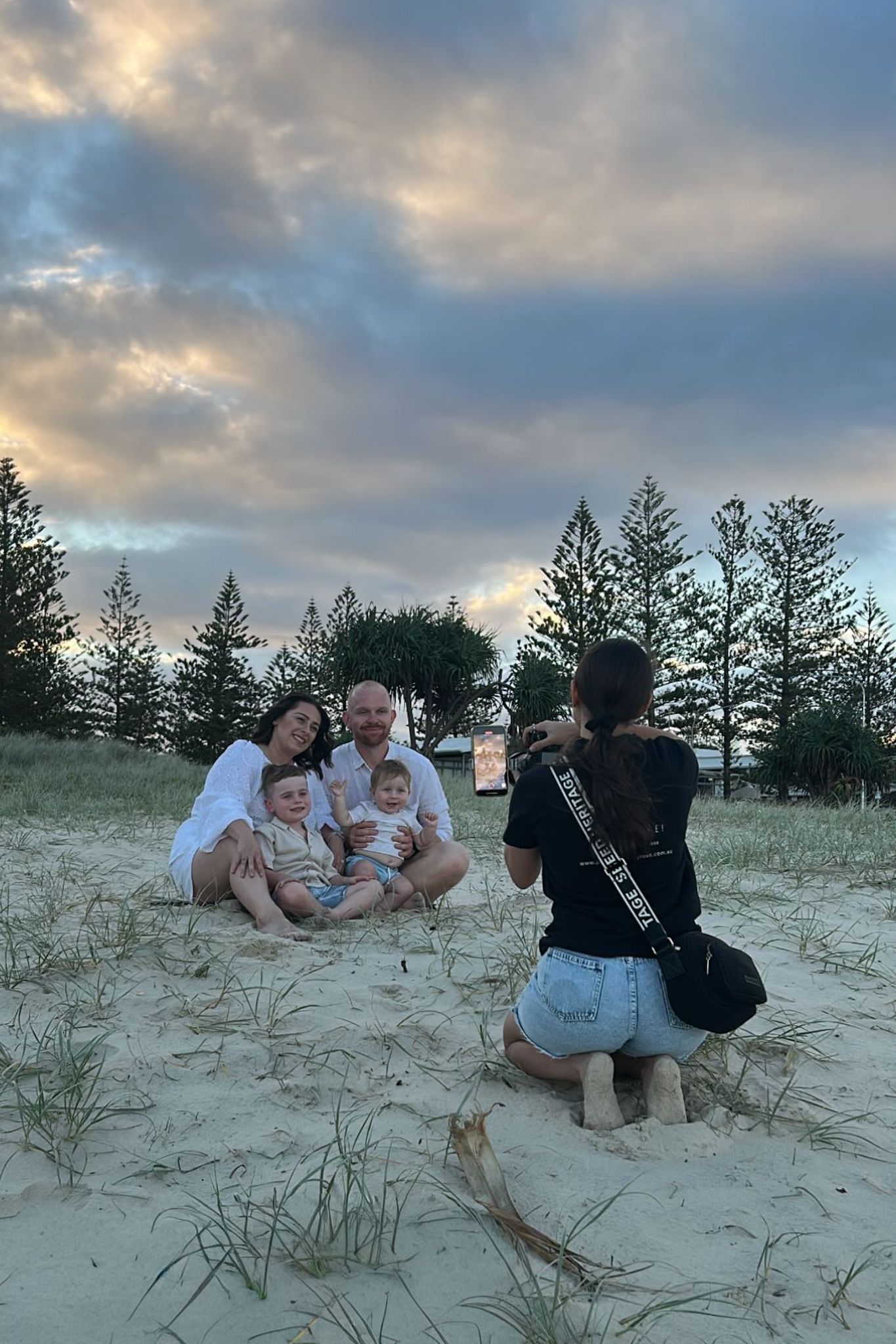 Photographer taking pictures of a family sitting on the sand on beach during sunset - Photos by Bailey Rose Gold Coast