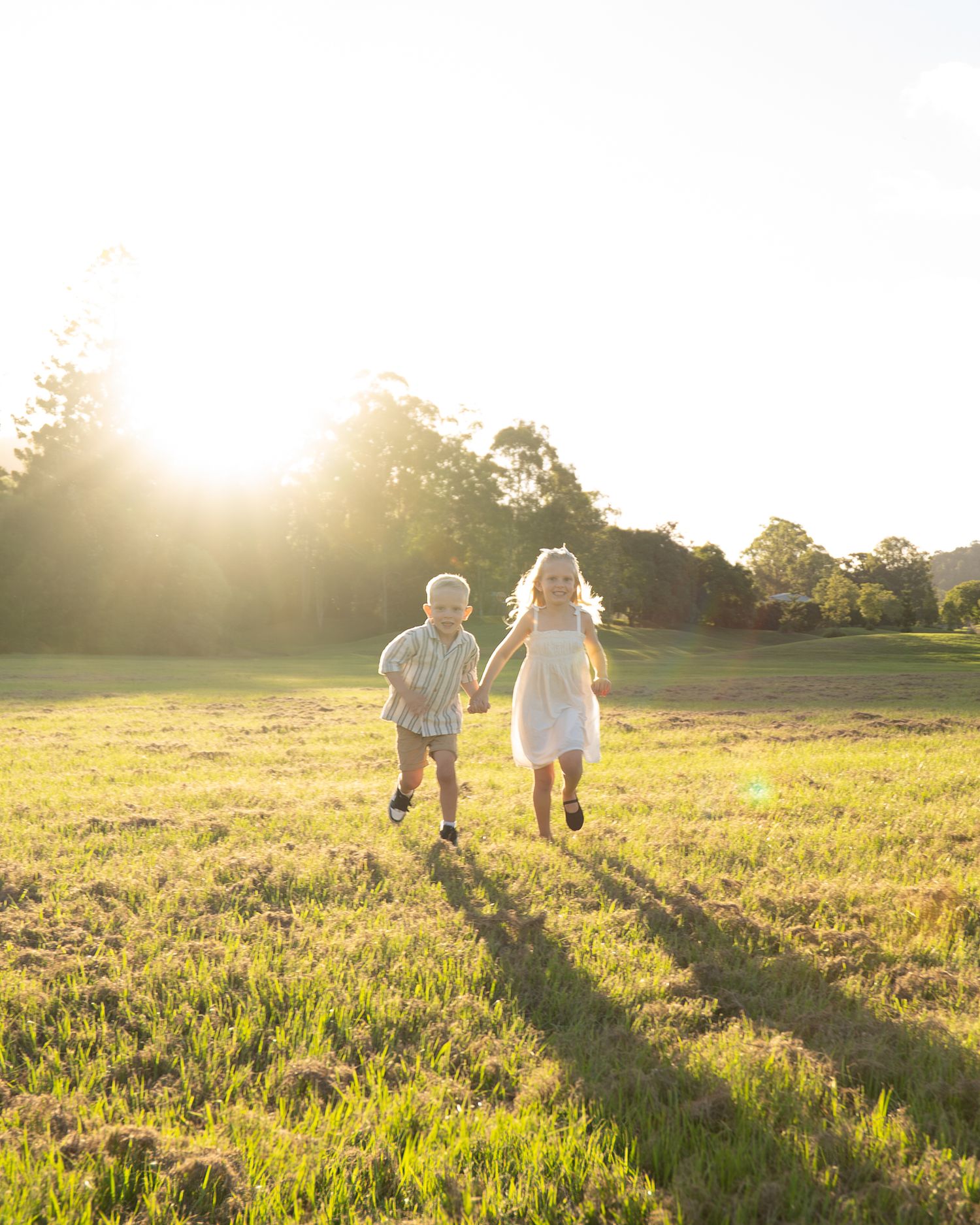 Two children running towards camera laughing in open field during golden hour - Photos by Bailey Rose Gold Coast Brisbane
