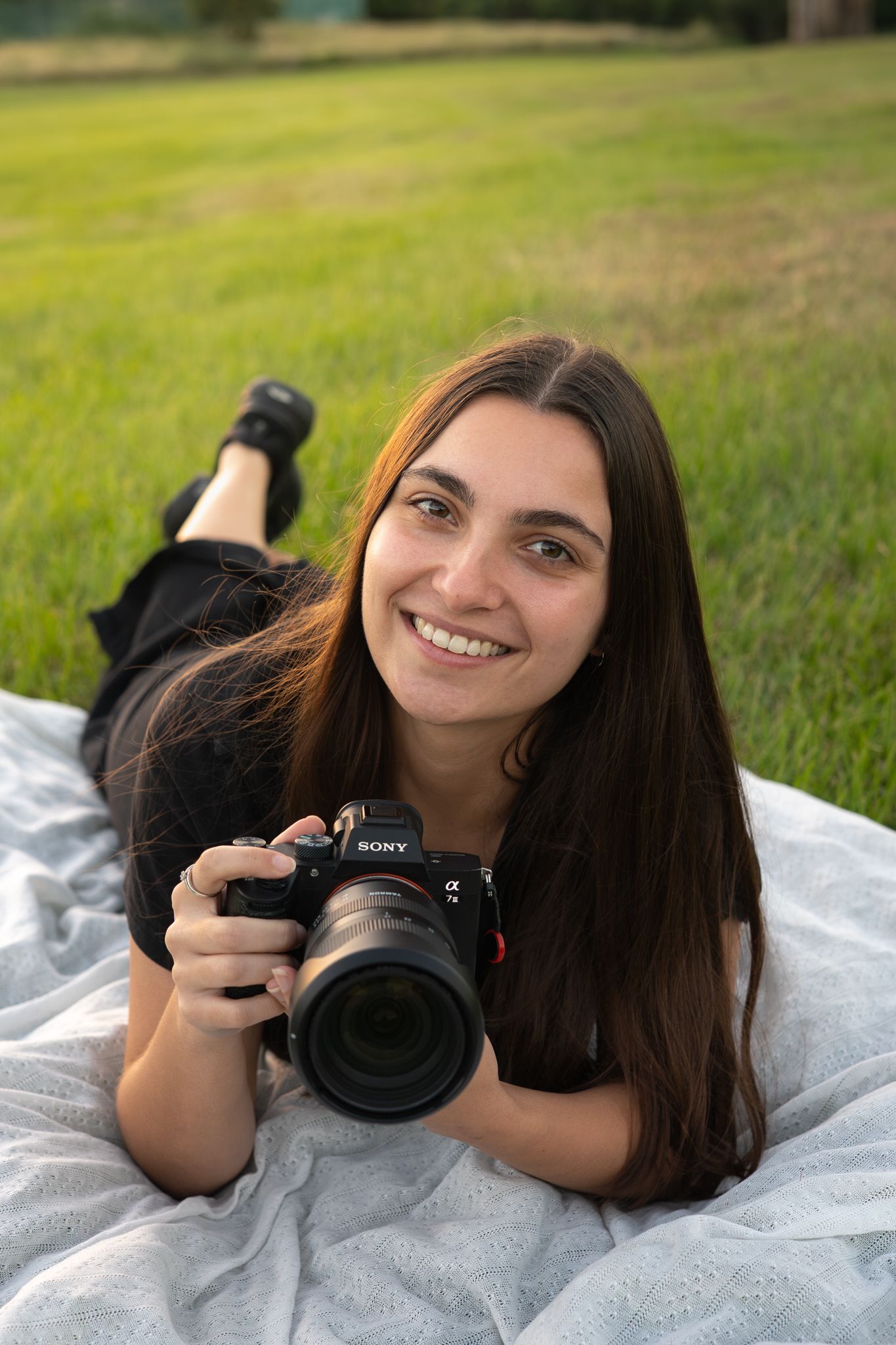 Bailey Rose lying with camera during outdoor portrait session