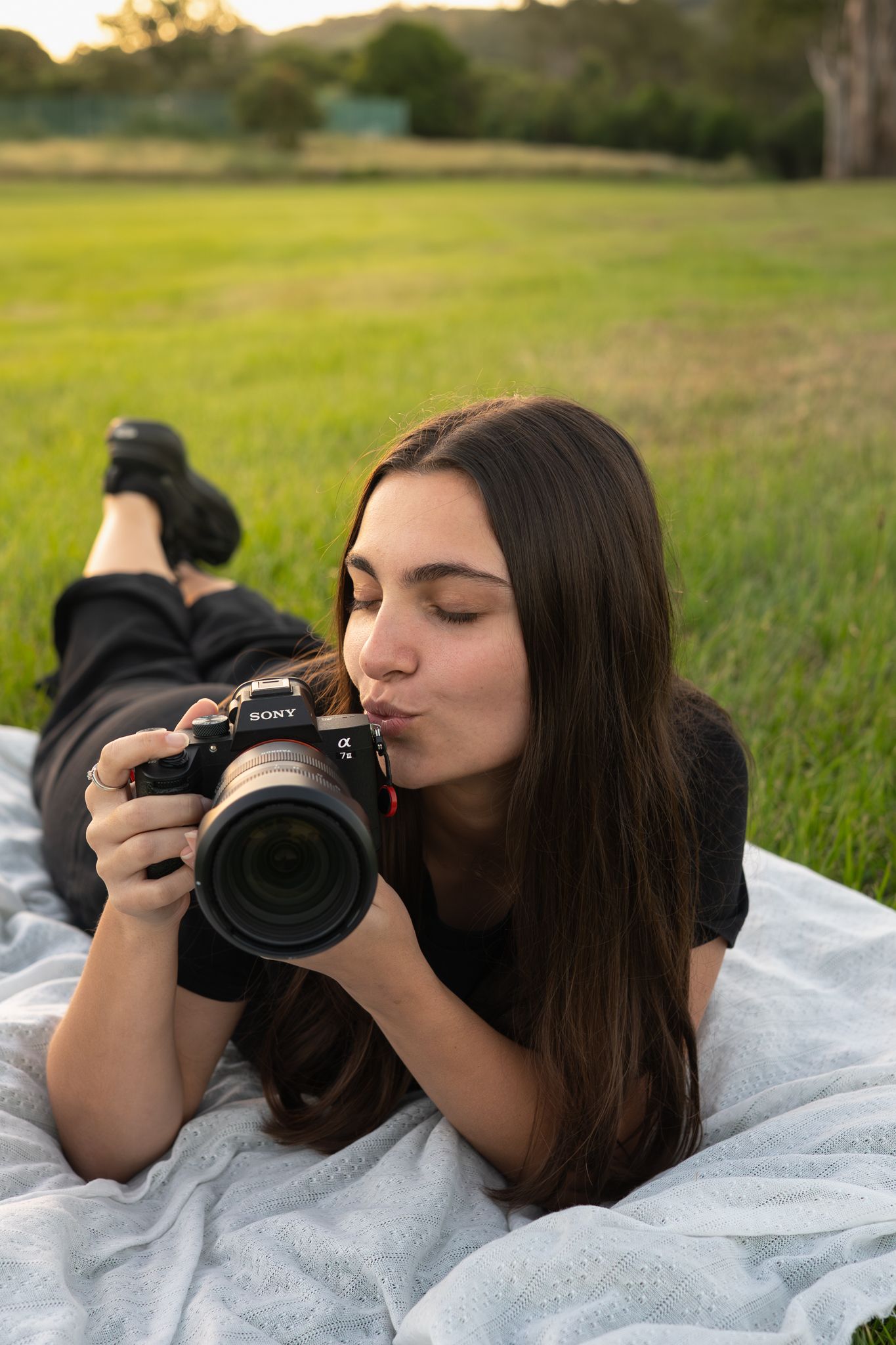 Bailey Rose lying with camera during outdoor portrait session