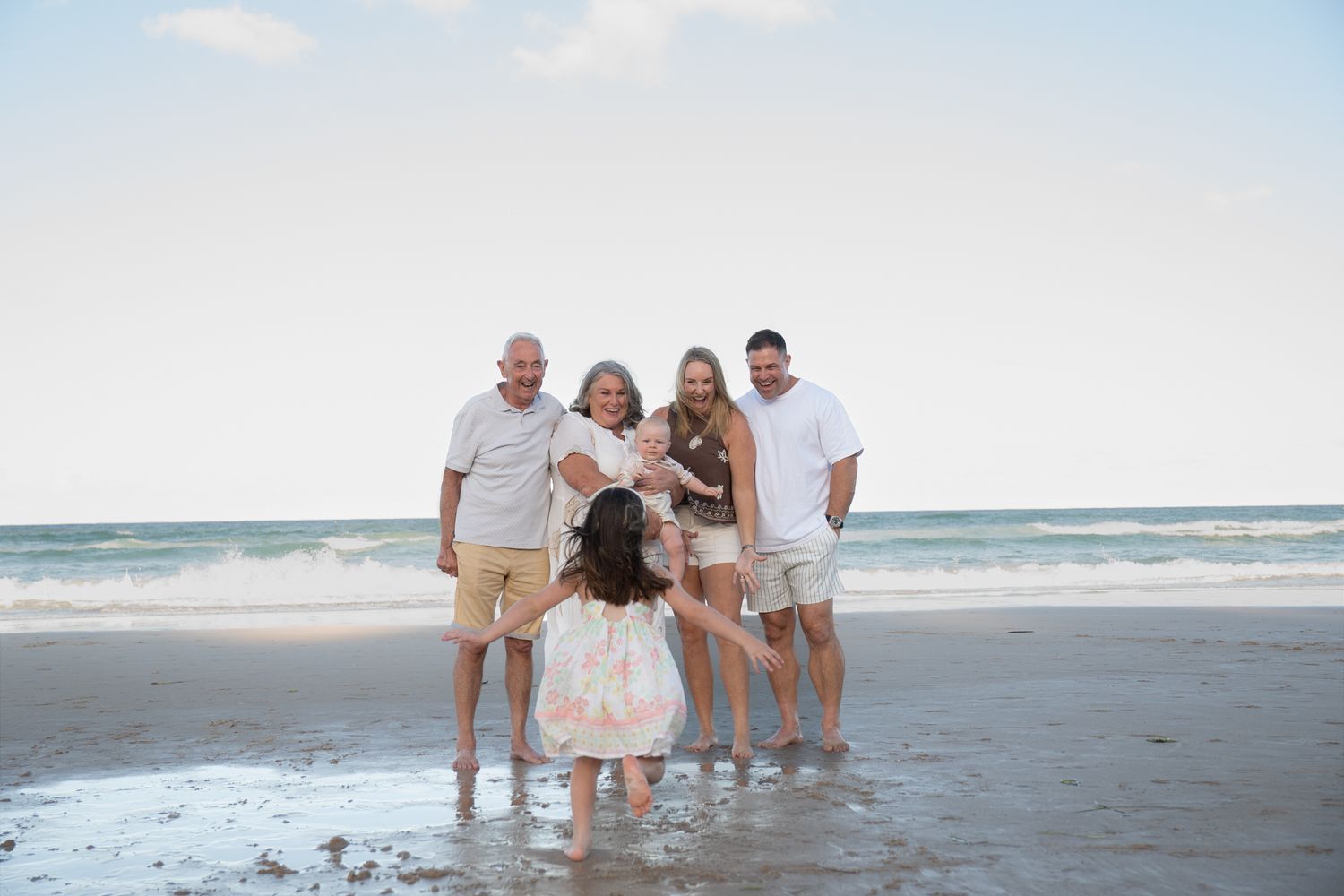 Family standing together on beach at golden hour child running towards — Photos by Bailey Rose Gold Coast