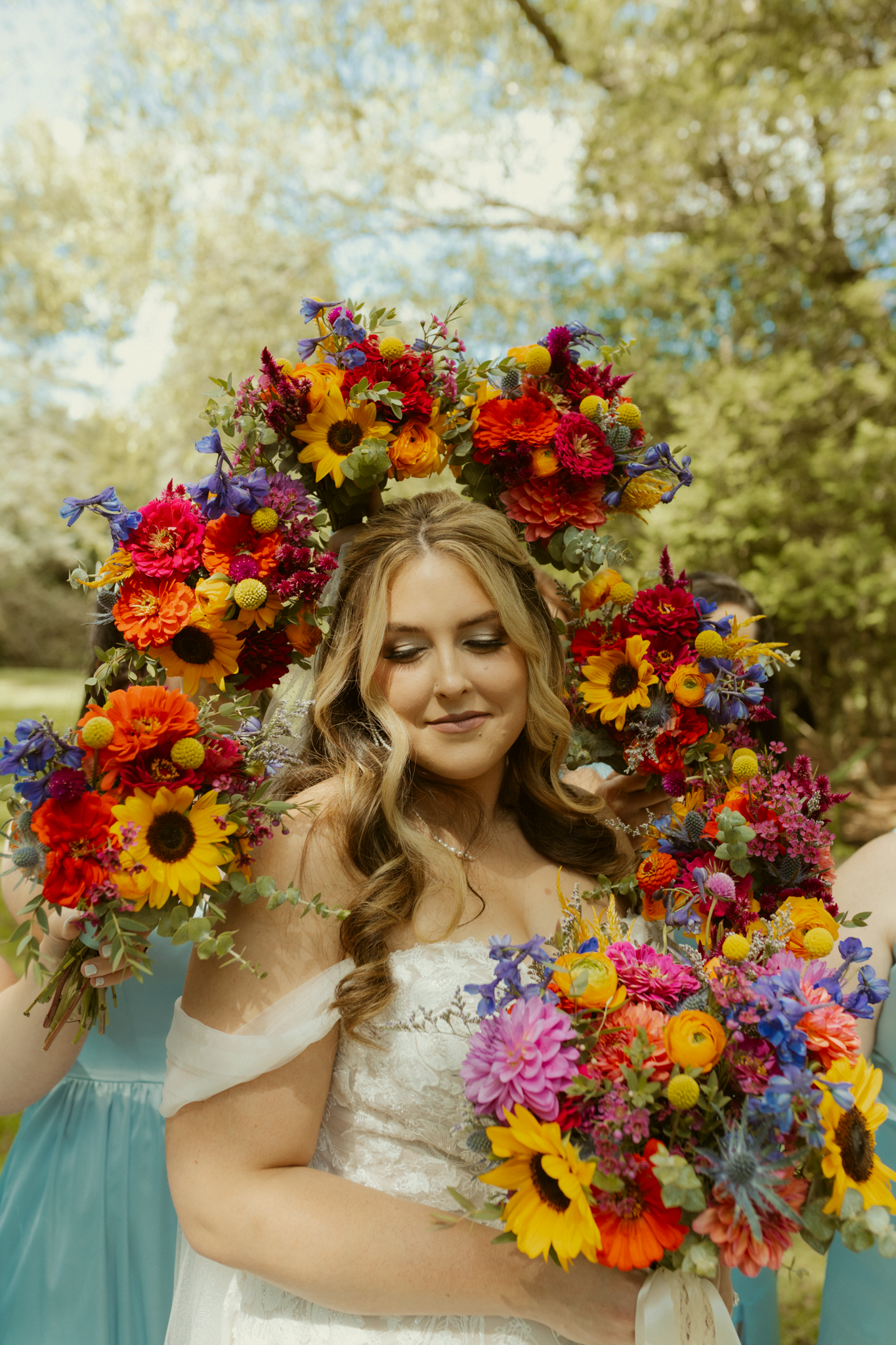 bride poses with bridesmaids and Vibrant wildflower wedding bouquets during summer wedding in Youngstown Ohio