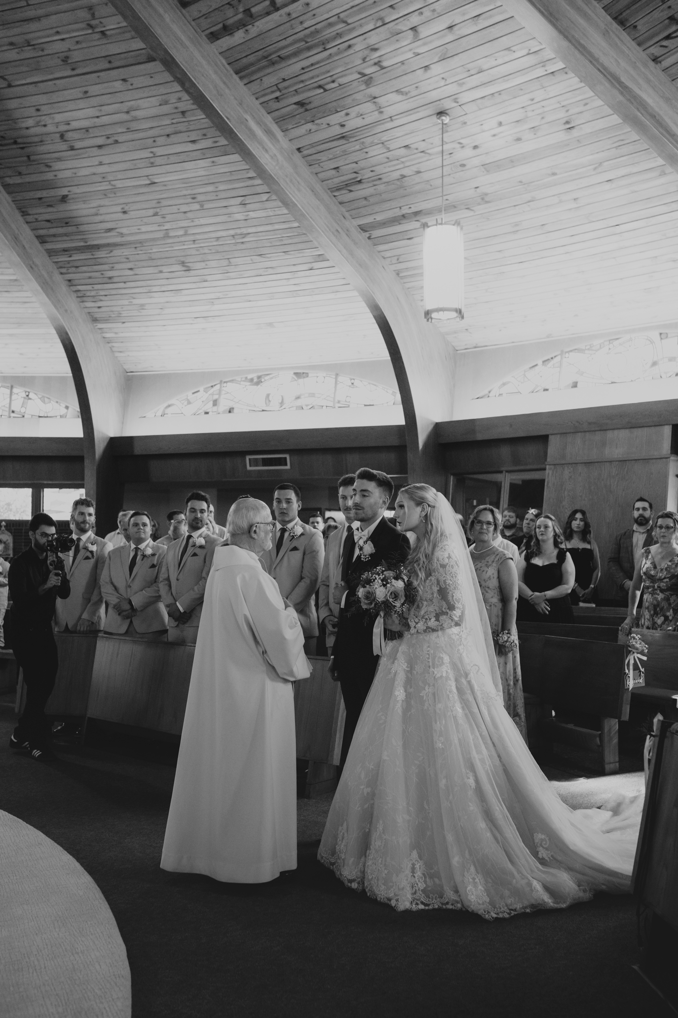 couple stands at the alter in a big Catholic Church for their wedding ceremony