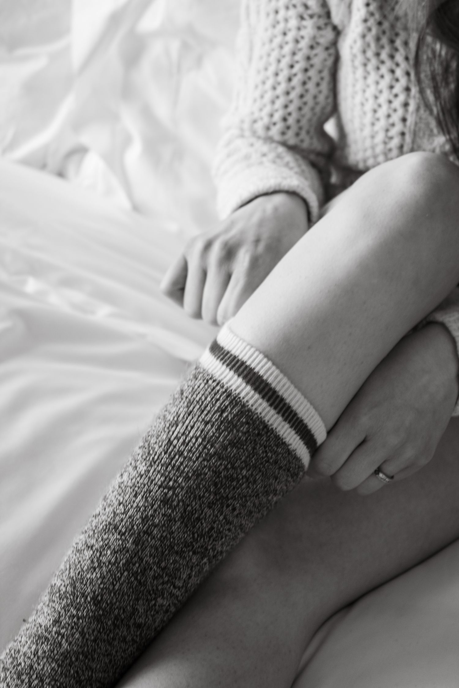 Detail shots of legs wearing knit socks against white bedding.