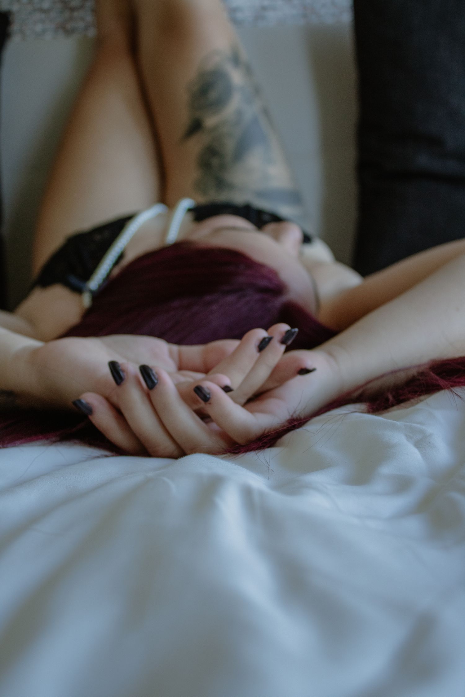 Intimate close-up of hands resting on white bedding.