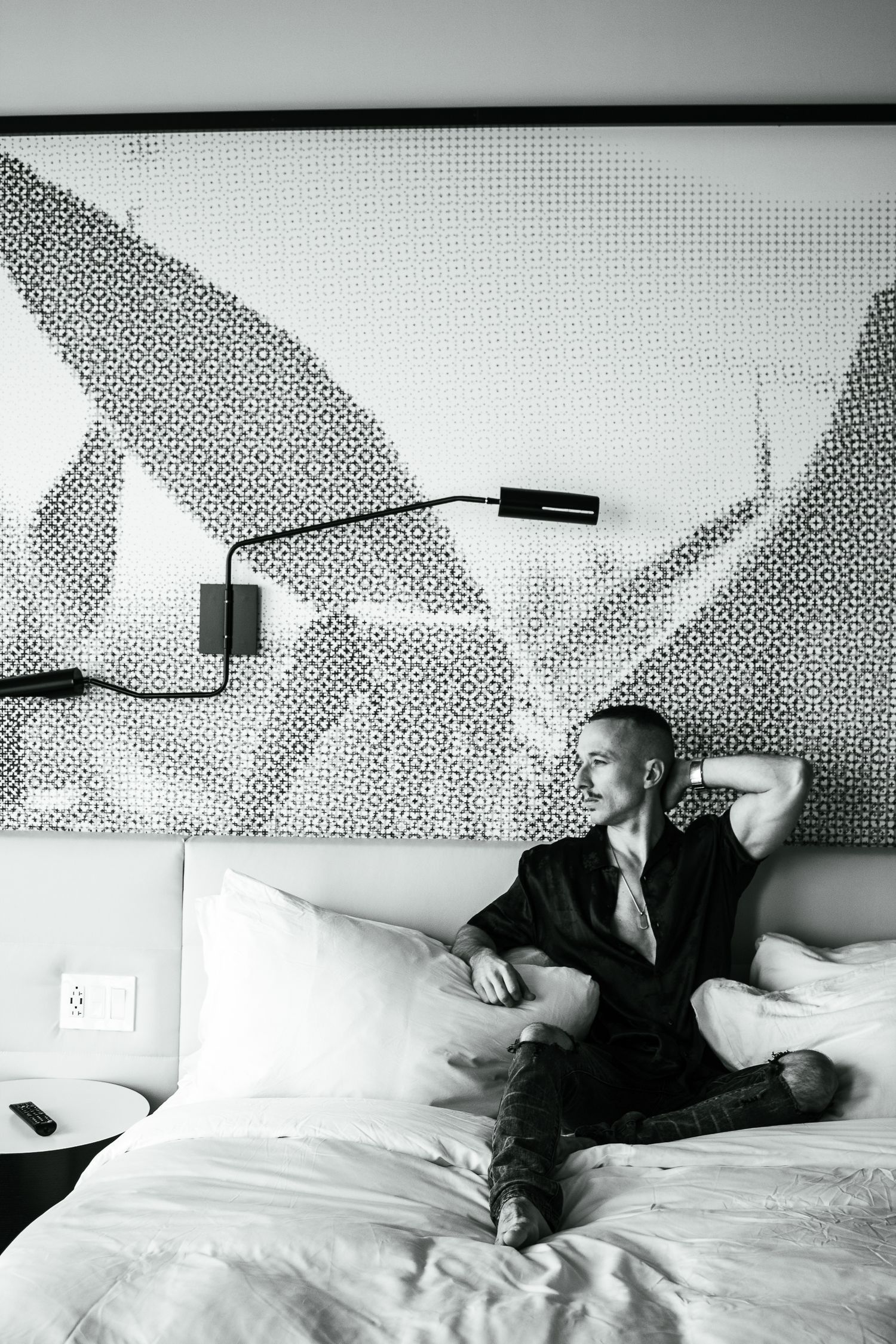 Black and white series of someone reclining on a bed against a patterned wall.