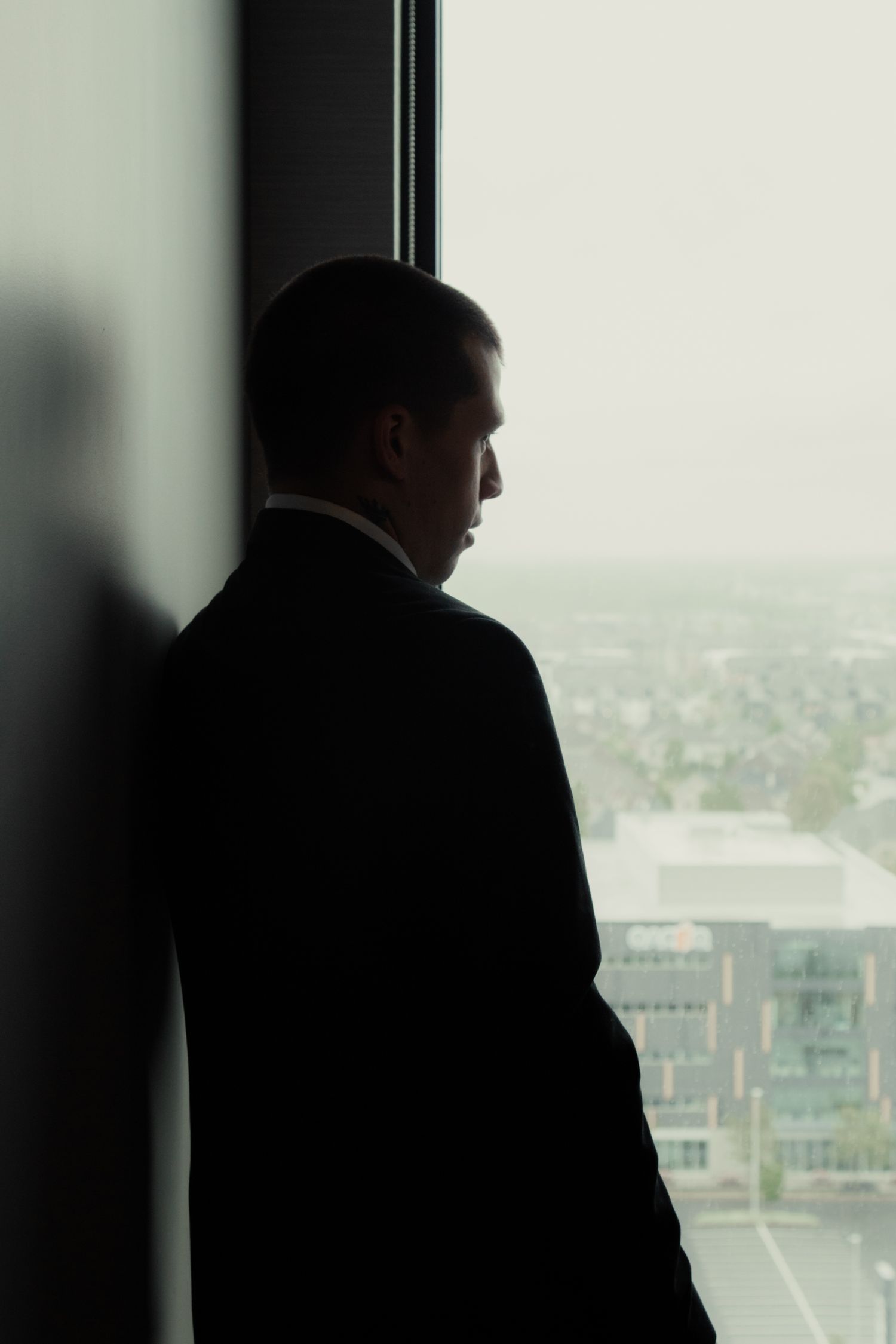 Silhouette of person in suit looking out window at cityscape.