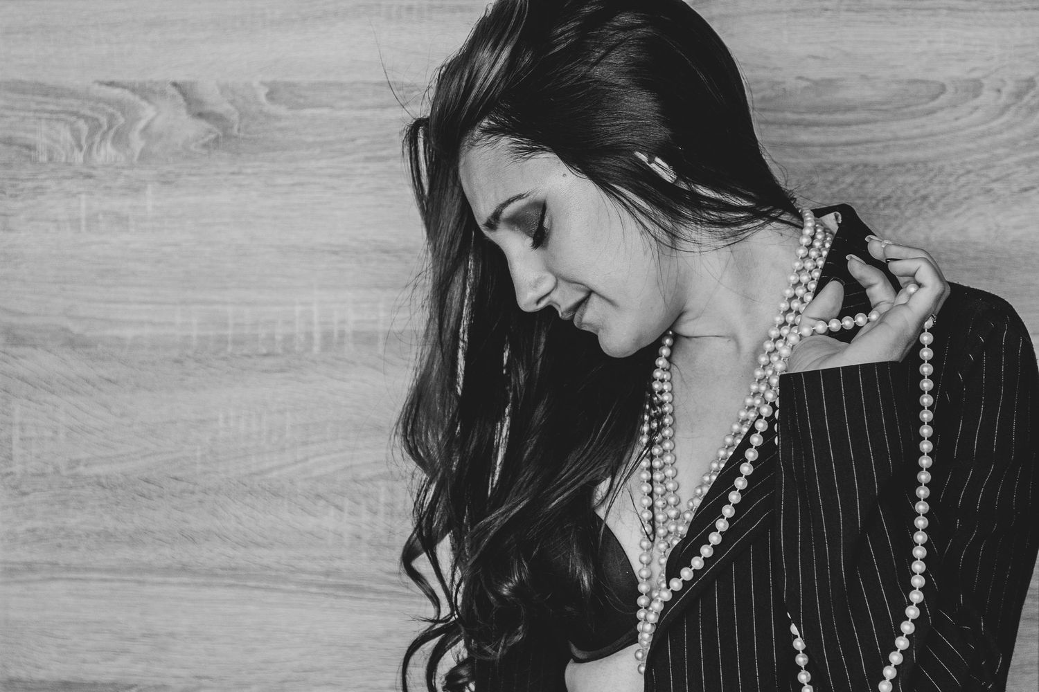 Moody portraits featuring pearl necklace and dark clothing in dramatic lighting.