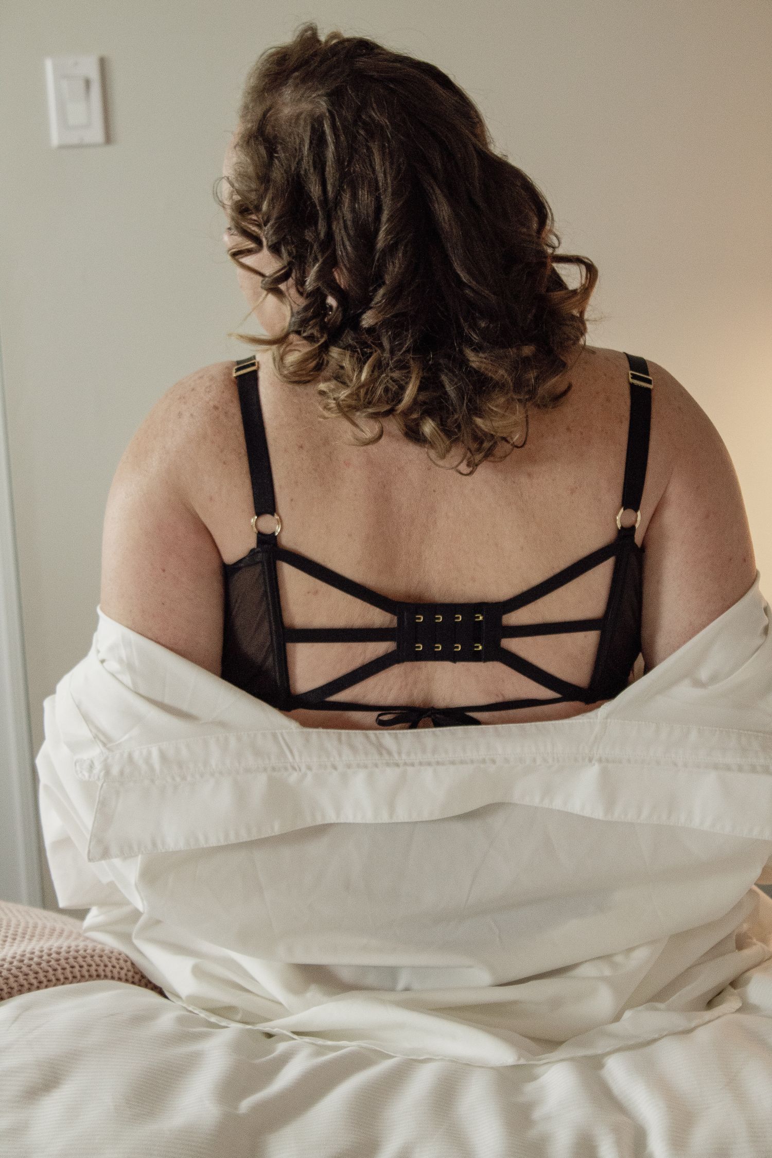 Close-up details of black strappy lingerie against white fabric.