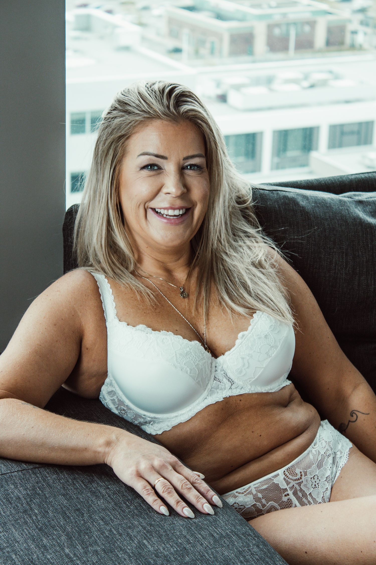 Intimate lifestyle photography on dark couch with white lingerie.