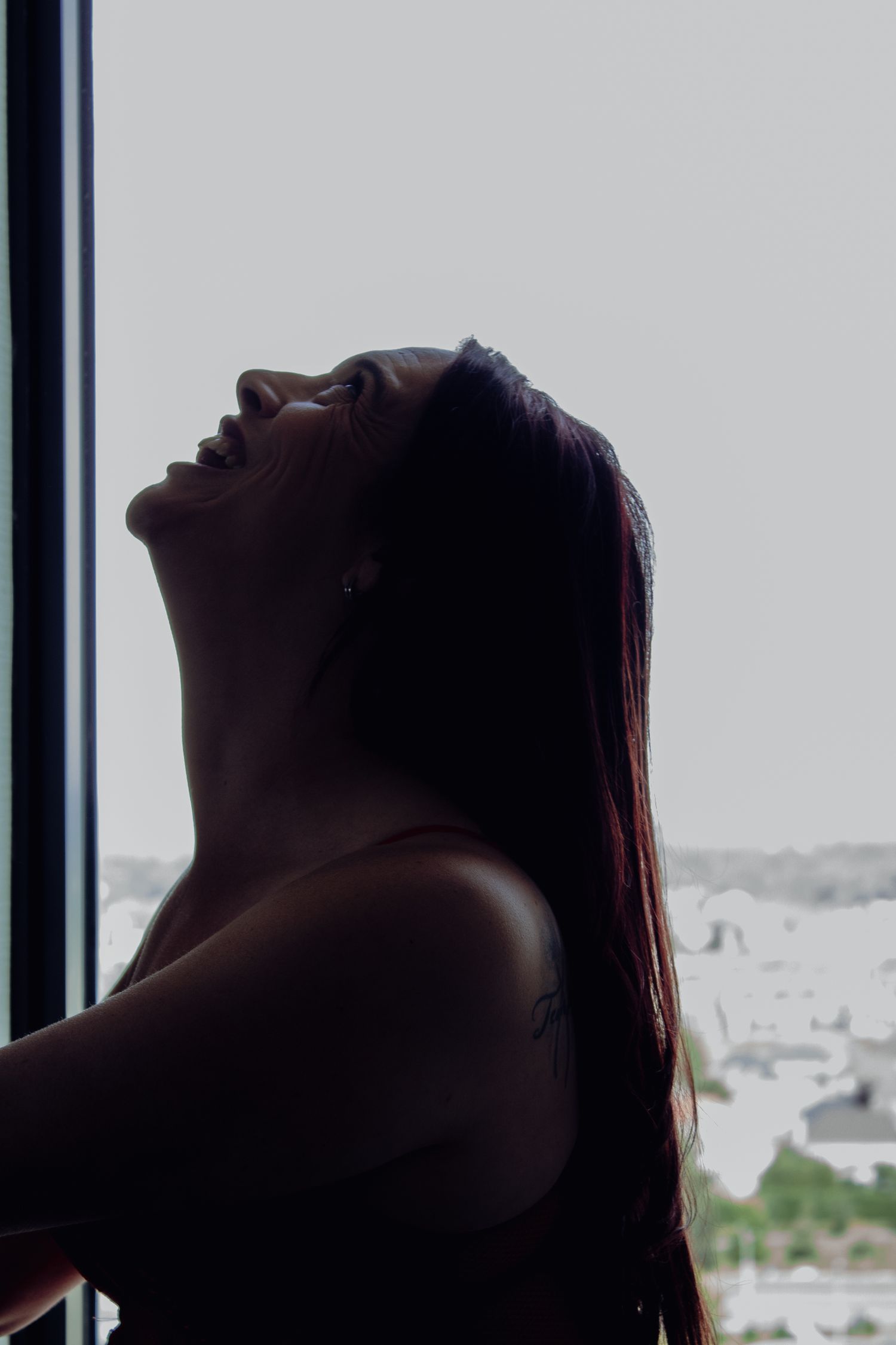 Silhouette profile against window showing urban landscape in background.