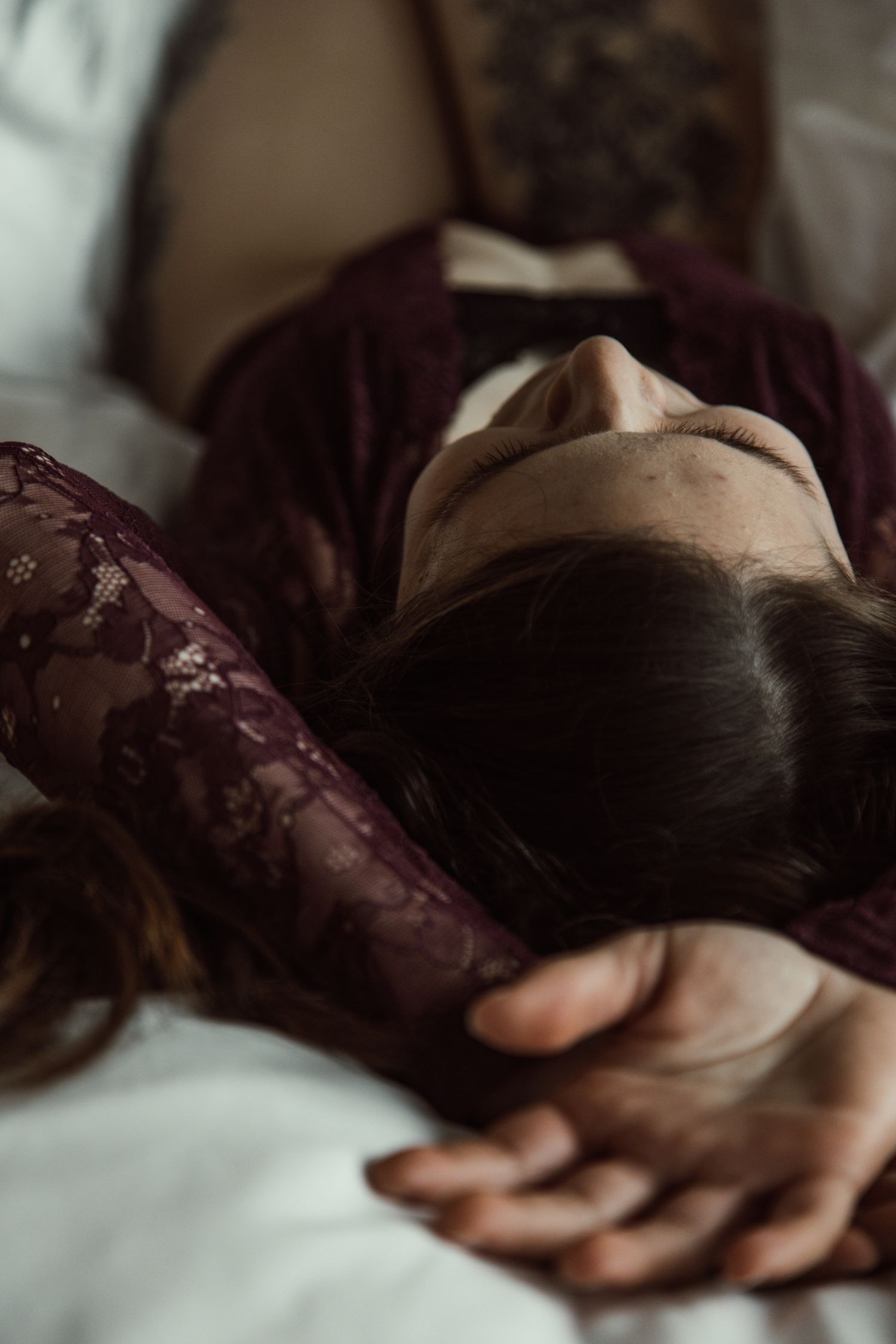 Artistic boudoir shots showing figure in purple lace lying on white bedding.