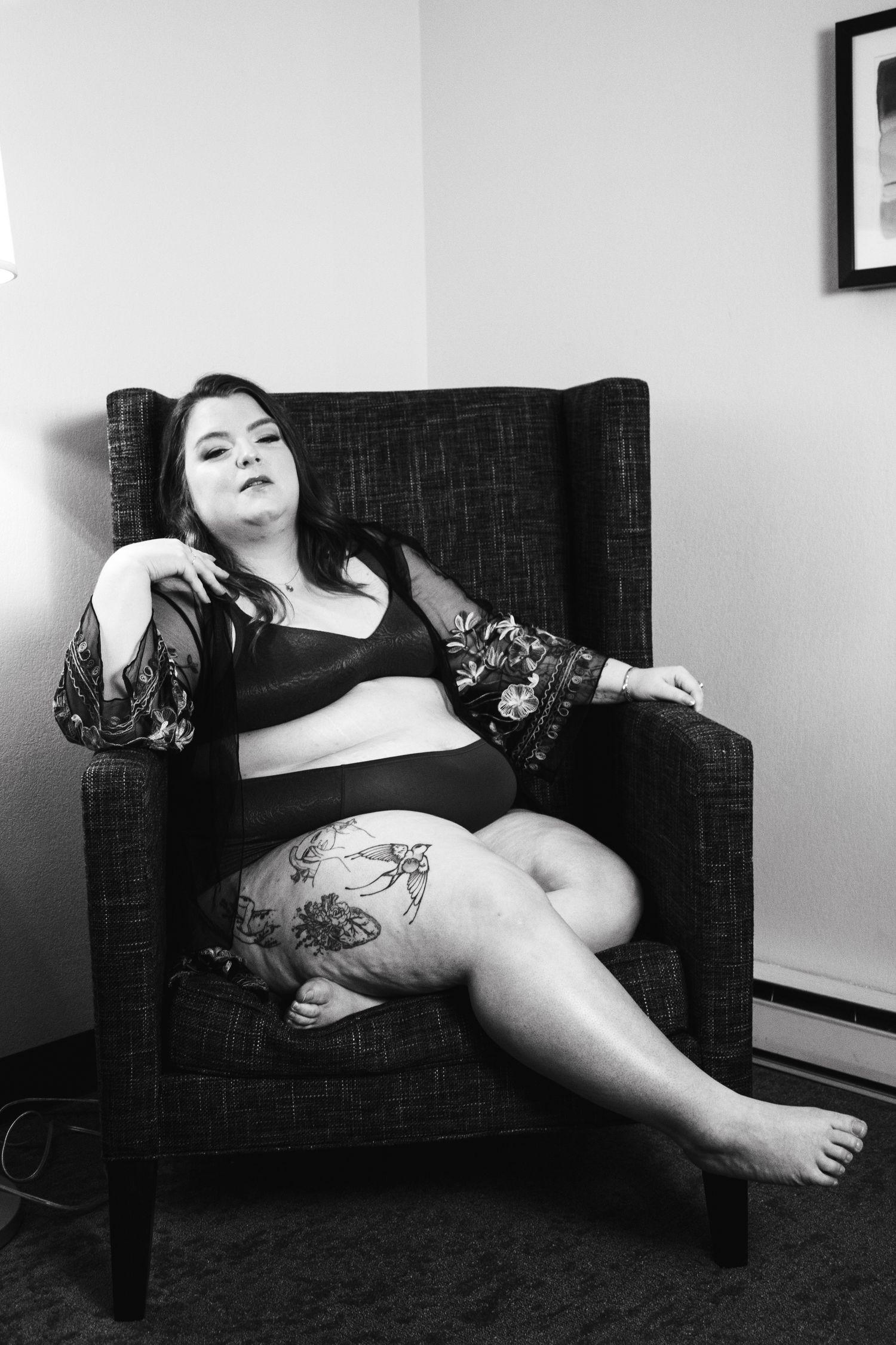 Intimate boudoir photography featuring tattoo art and dark furniture.