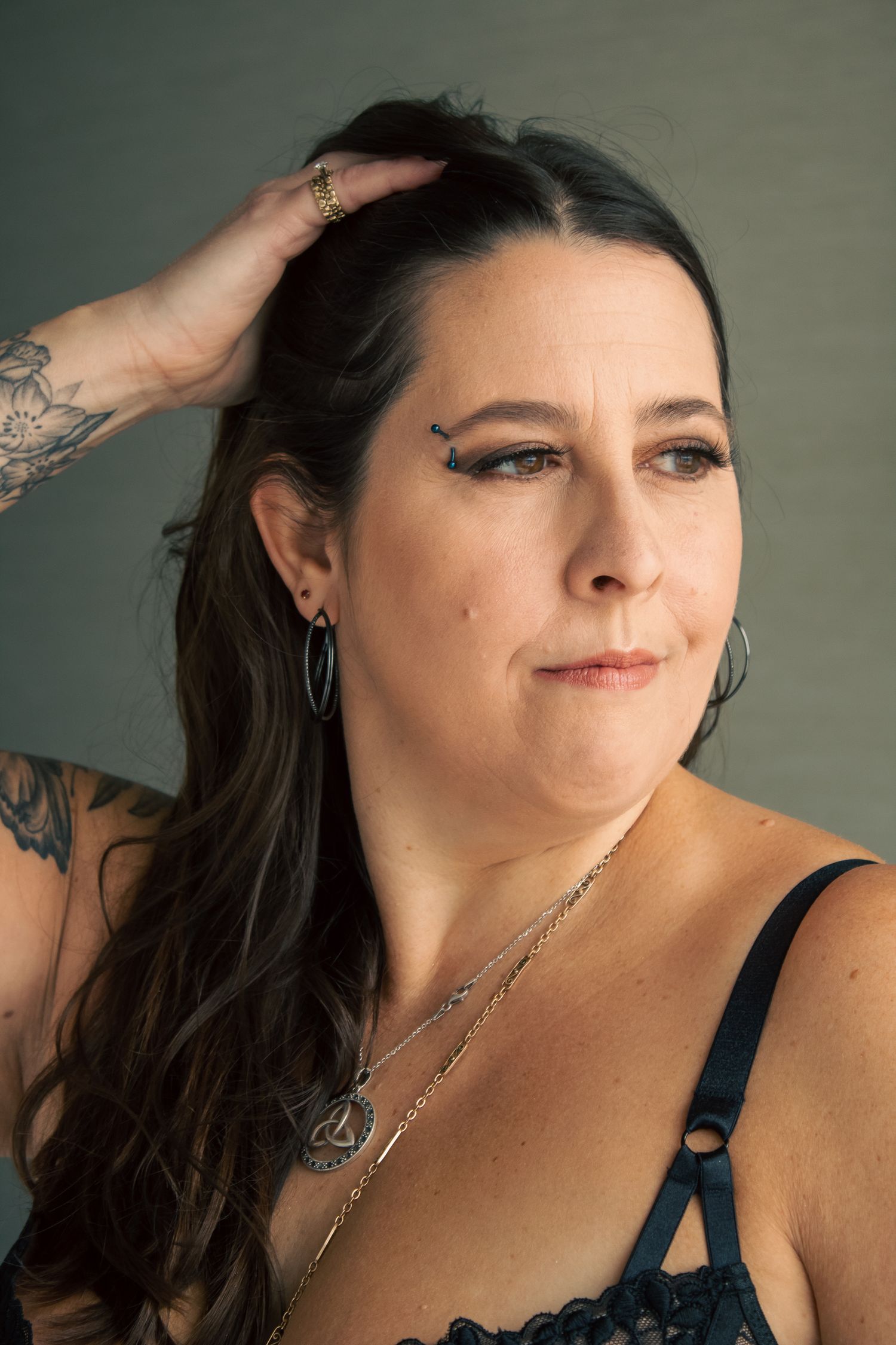 Close-up portrait series with silver jewelry and dark top.