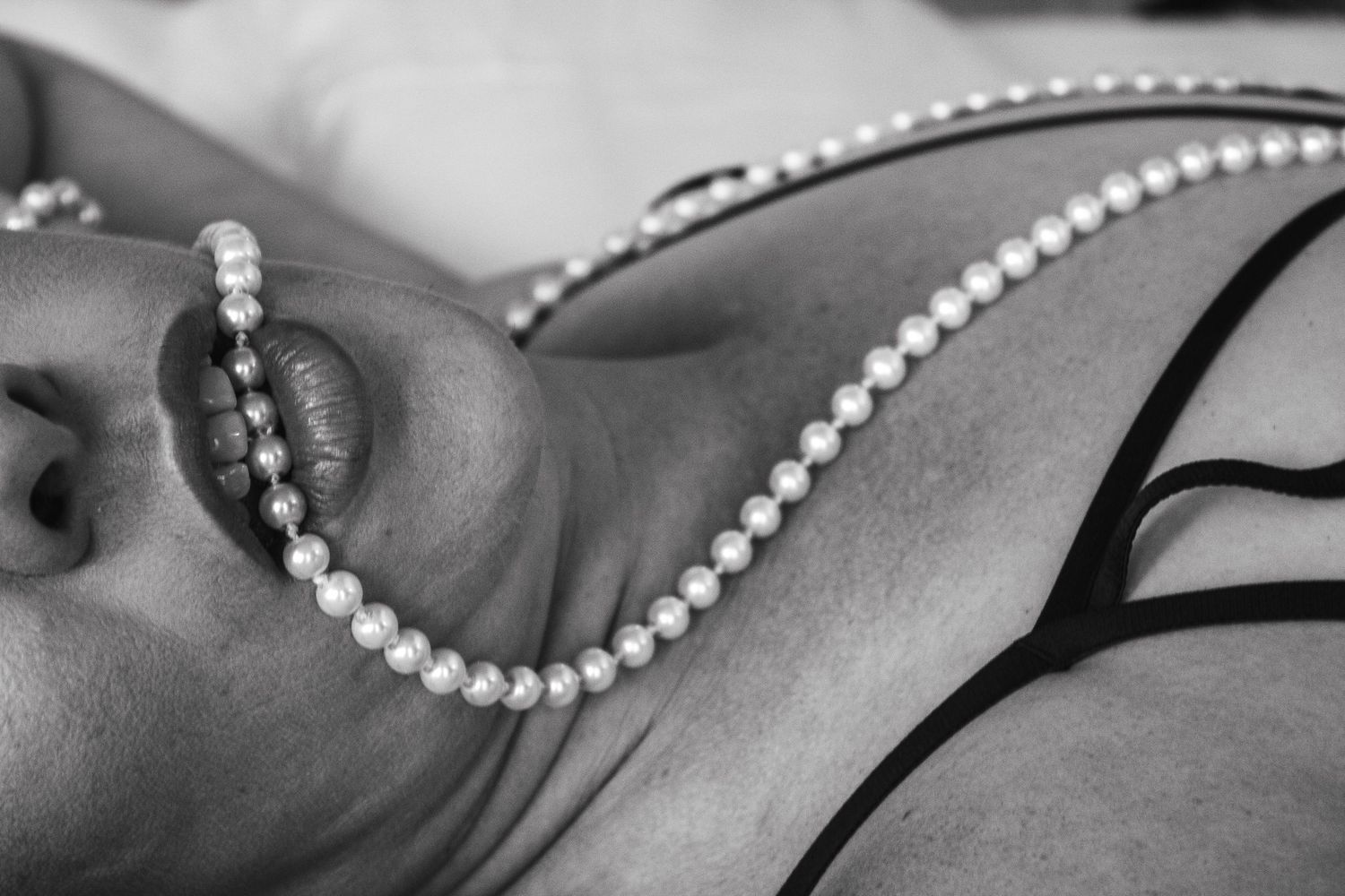 Close-up of pearl necklace against dark lingerie.