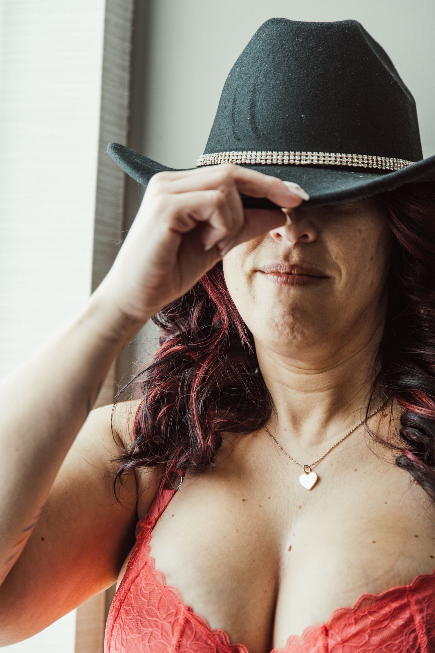 Person wearing a black hat and coral top poses in a series of artistic shots.