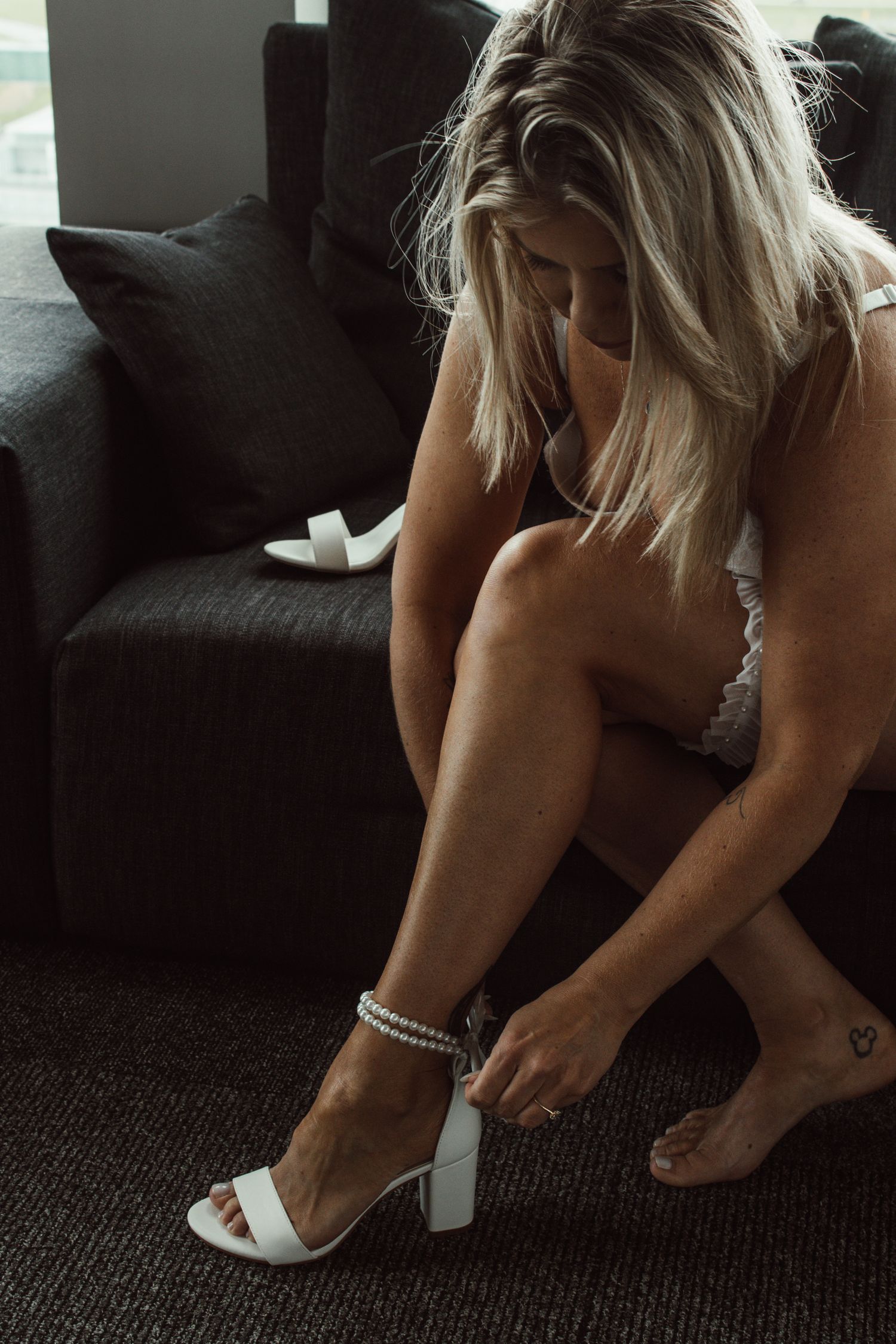 Candid lifestyle photography showing pearl bracelet and white heels.