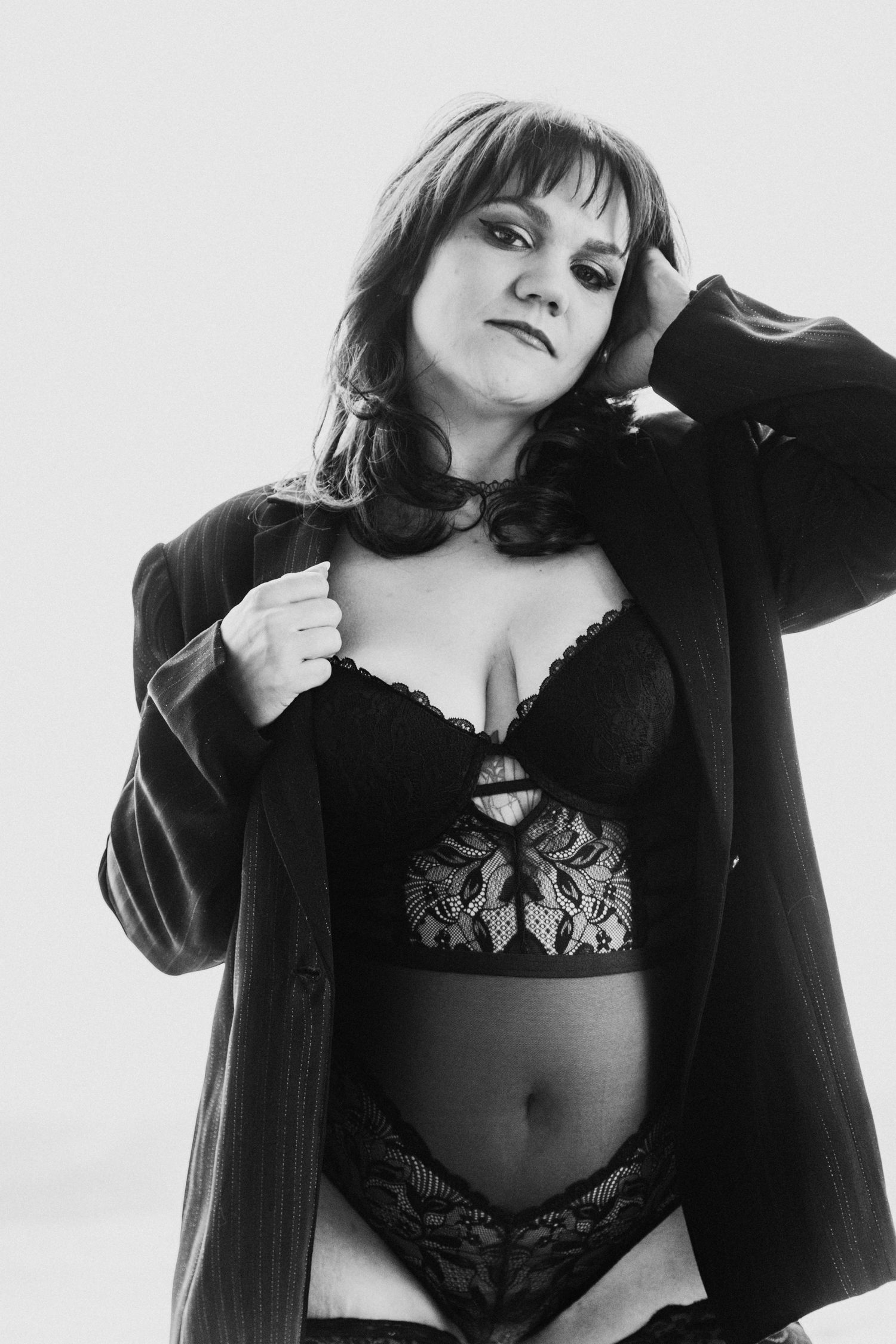 Black and white portrait featuring person in lace lingerie and open cardigan.