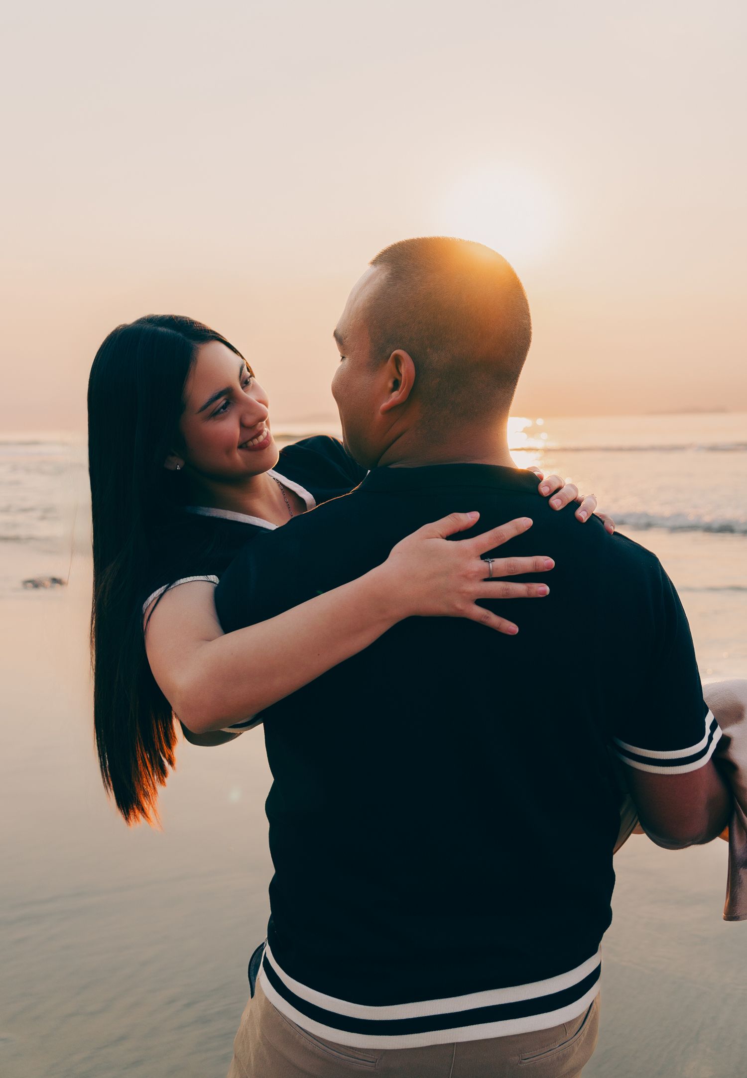Novio cargando a novia durante su sesion de fotos en playas de Tijuana