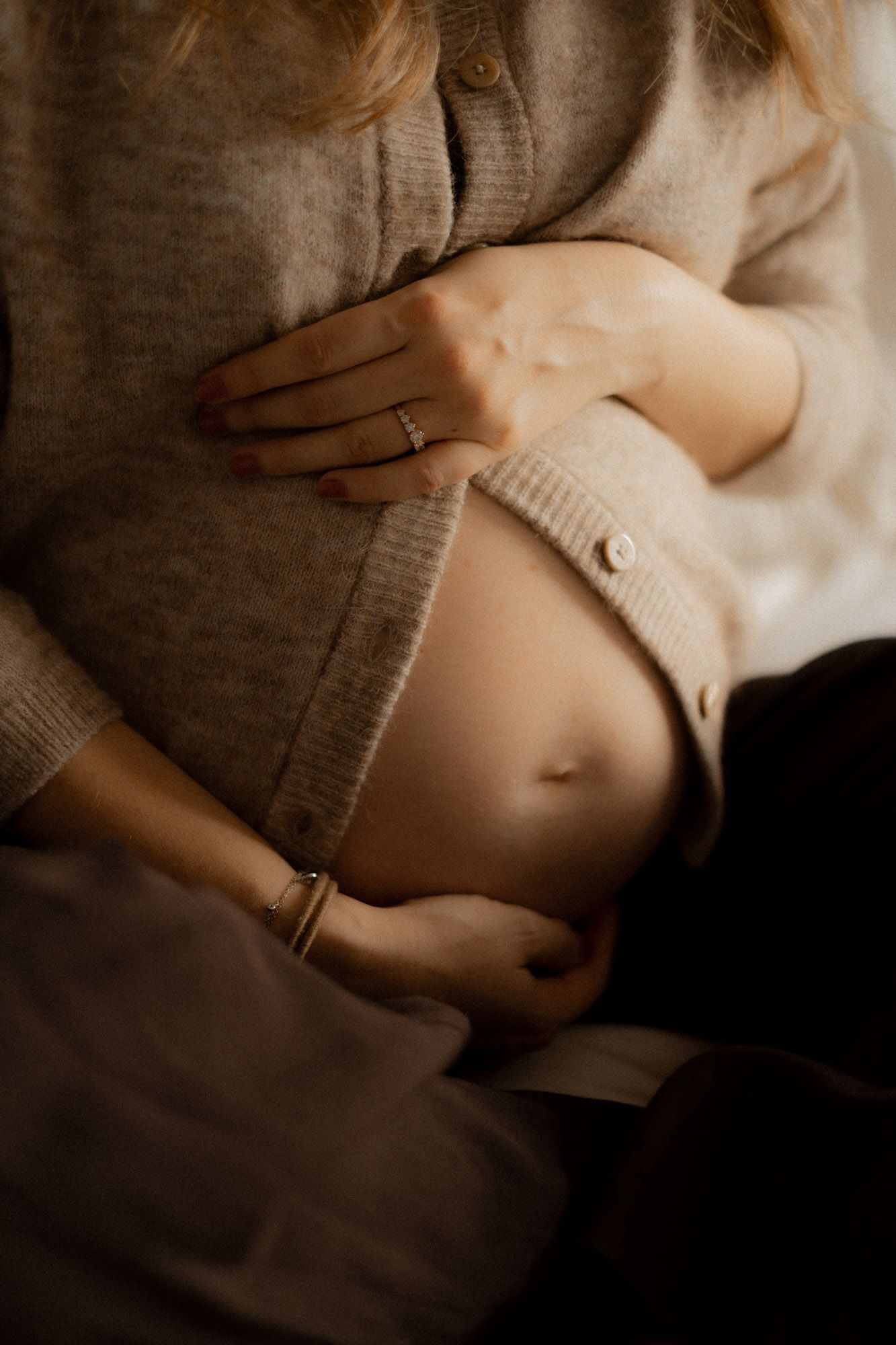 Gros plan de ventre de femme enceinte à Montréal, séance grossesse en lumière naturelle et douce, style artistique.