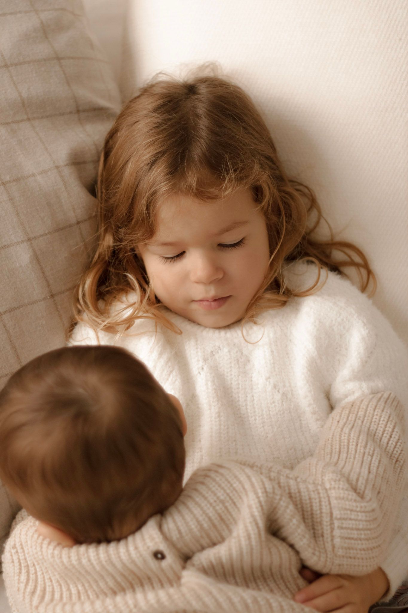 Deux jeunes enfants en pulls blancs partageant un moment tendre