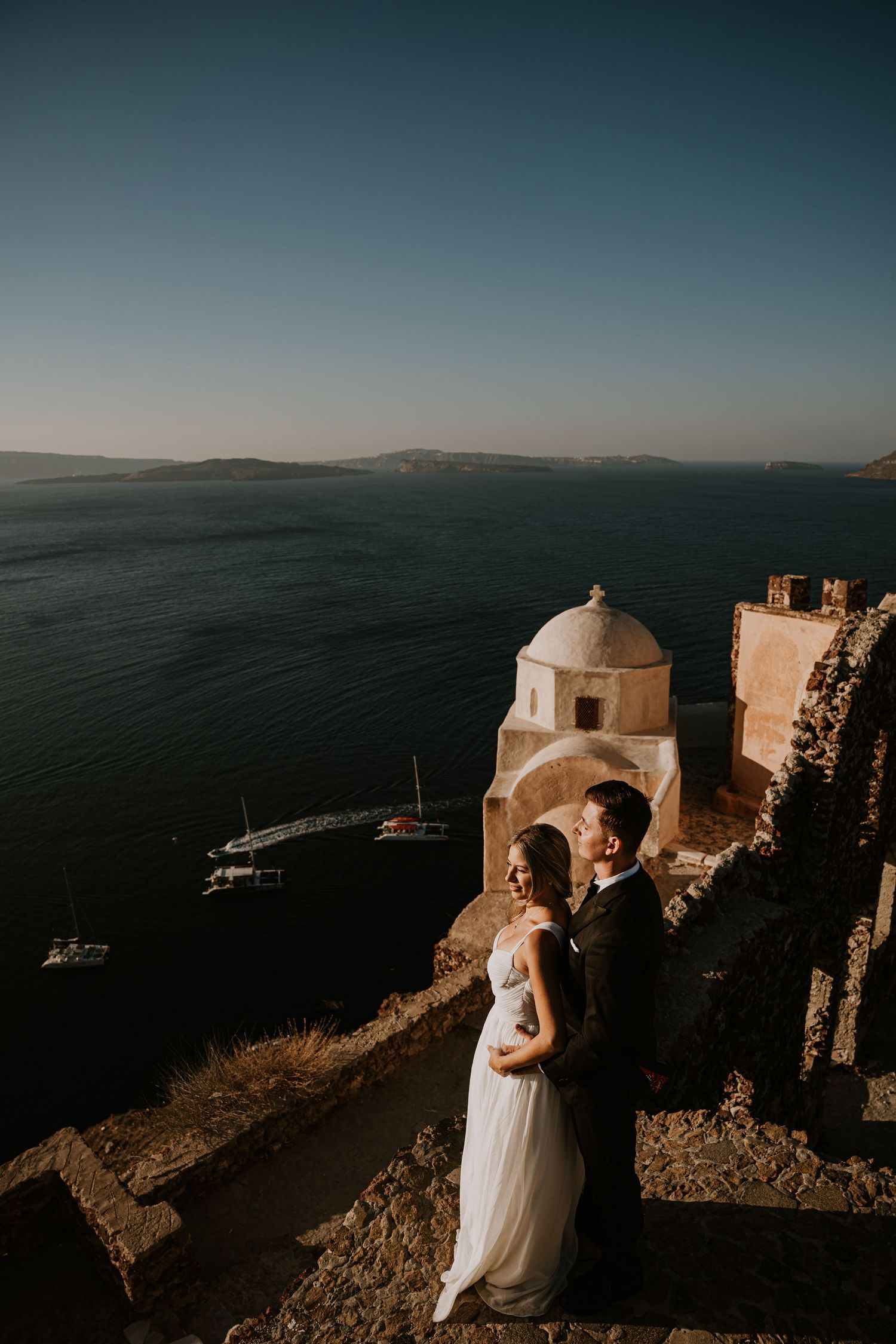 Wedding photography featuring white domed churches and dramatic views of the Aegean Sea.