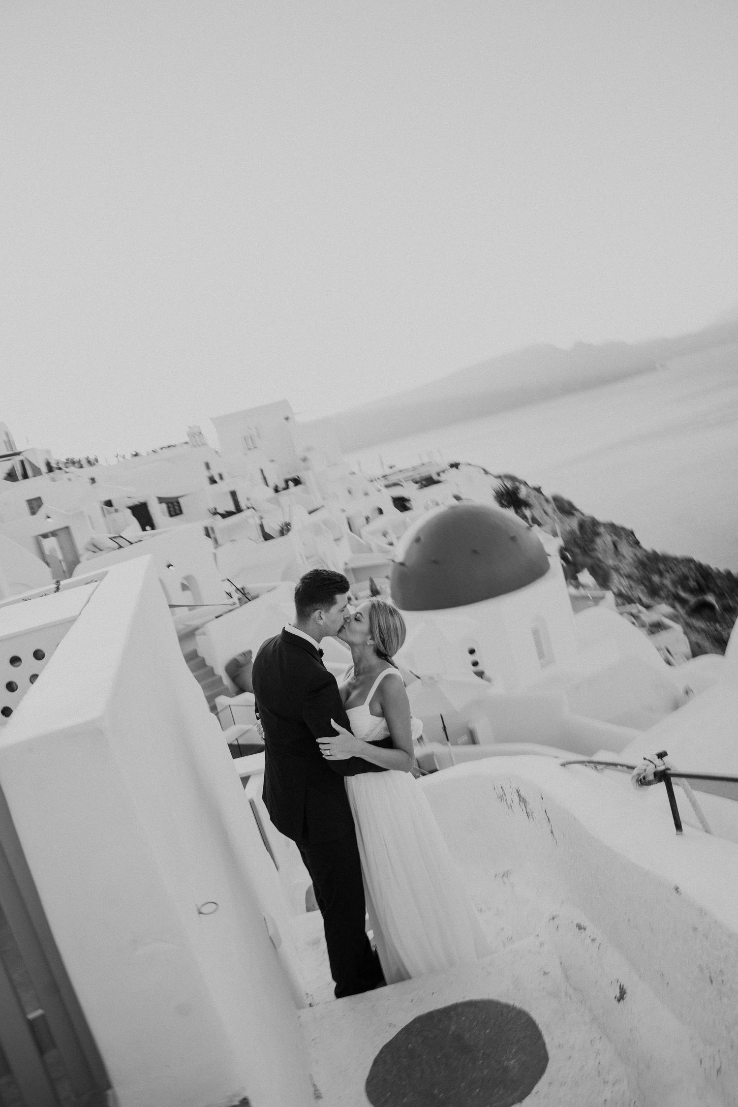 Black and white photo of a wedding couple on Santorini's traditional whitewashed terraces.