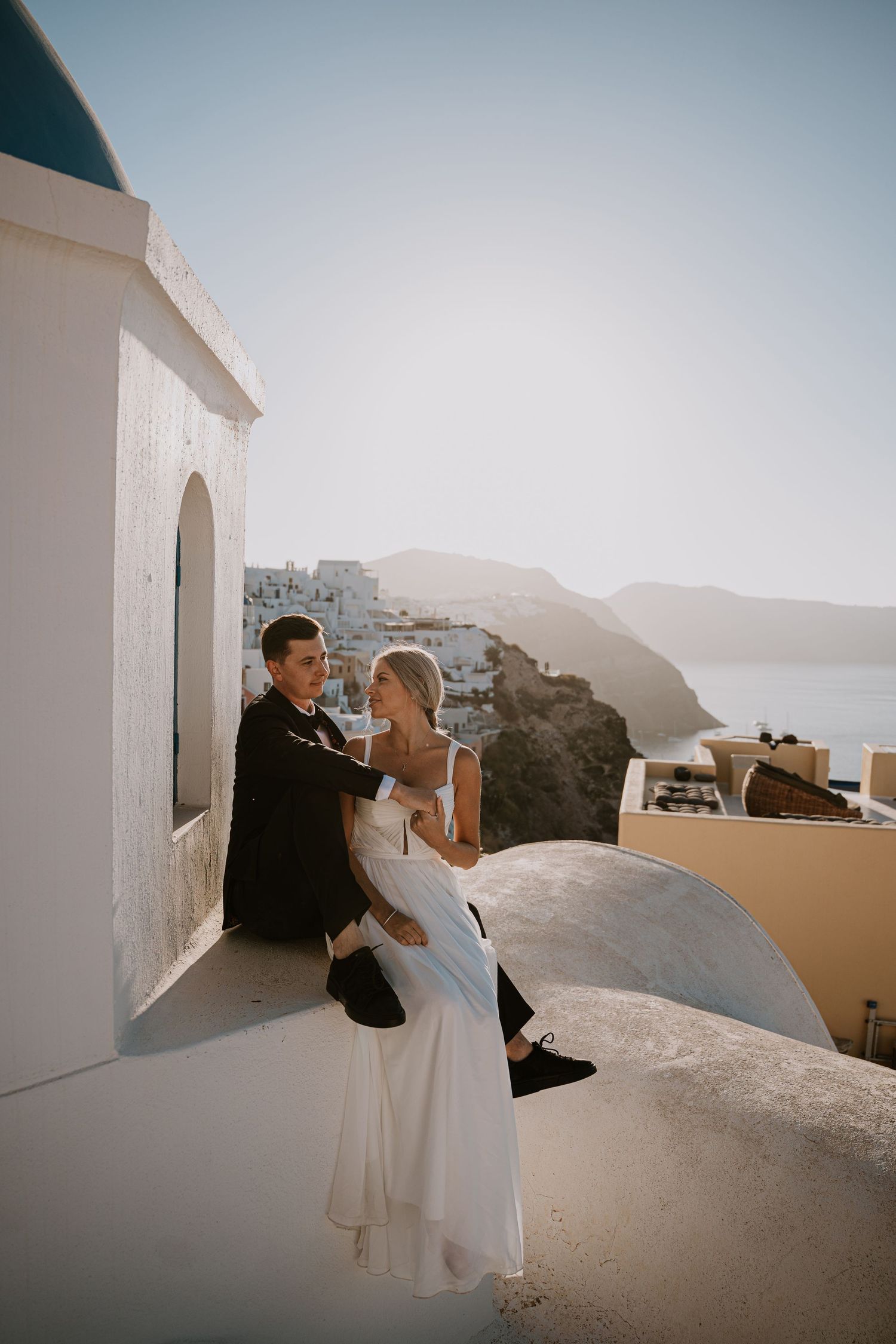 Romantic wedding photo against white architecture and blue domes of Santorini.