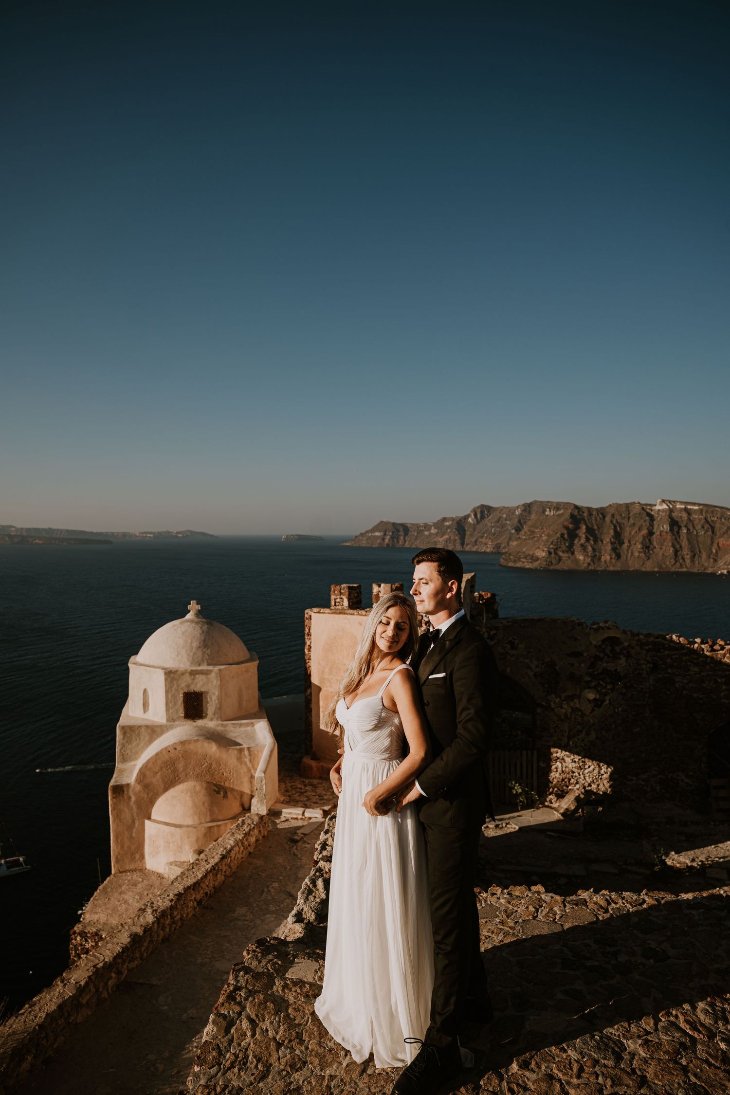 A romantic photoshoot at golden hour showcasing Santorini's iconic white architecture and sea views.
