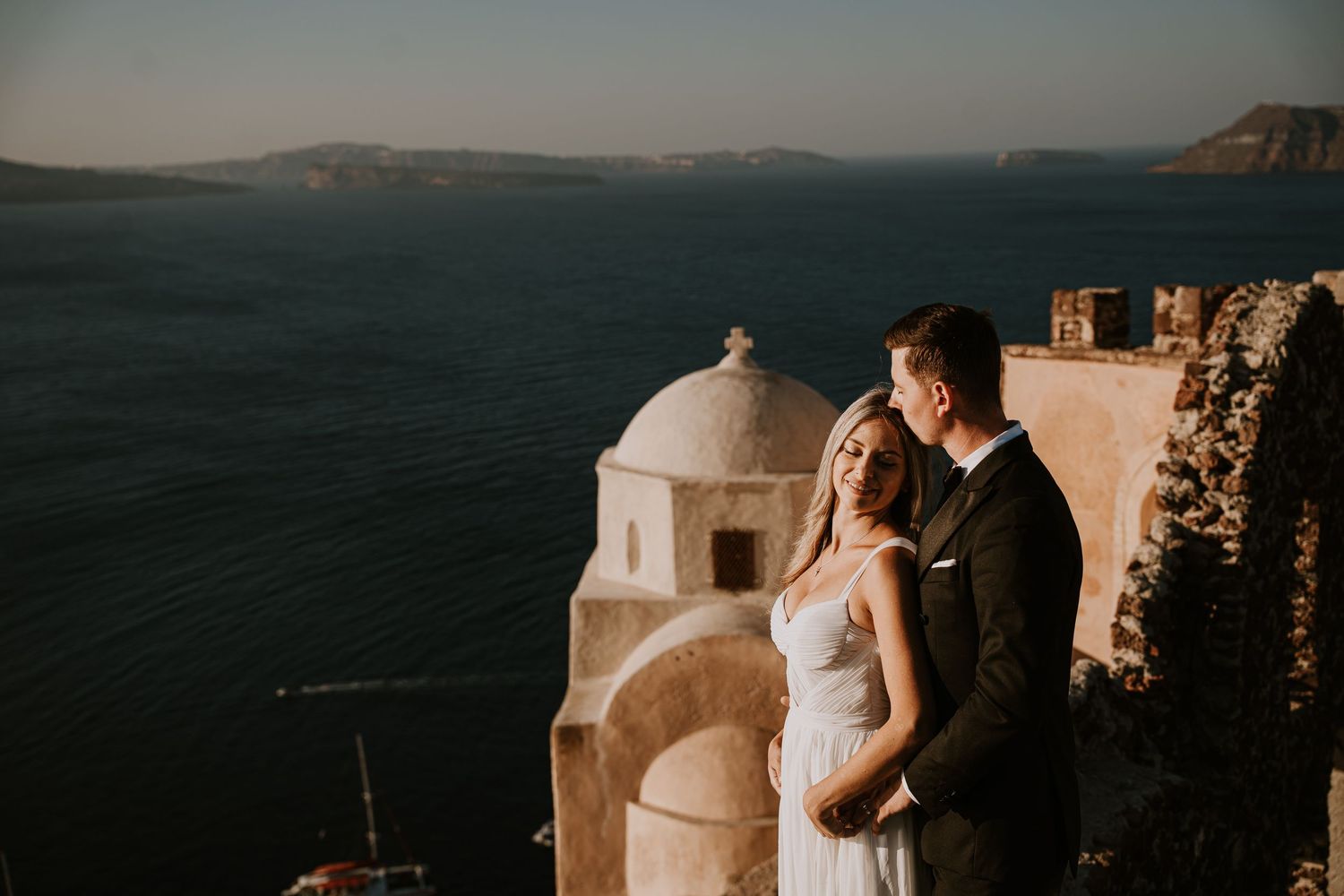 Sunset wedding photography featuring white Mediterranean architecture and dramatic ocean views.