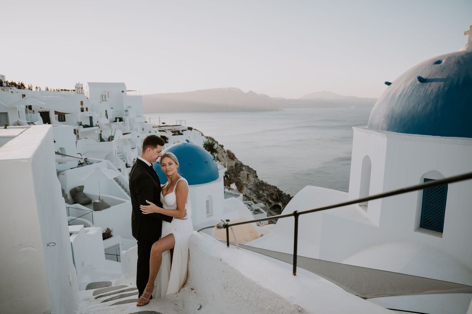 Newlyweds share an intimate moment on white steps overlooking the Mediterranean Sea in Santorini.