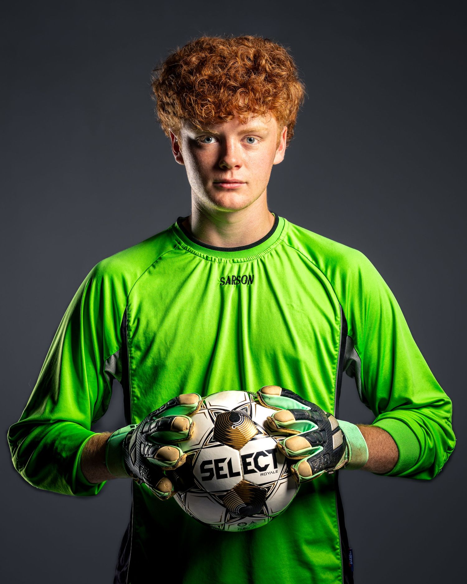 Dramatic studio athletic portrait of a varsity soccer goalkeeper in neon green kit with soccer ball by Sporty-Clips Media in Fairfax, VA.