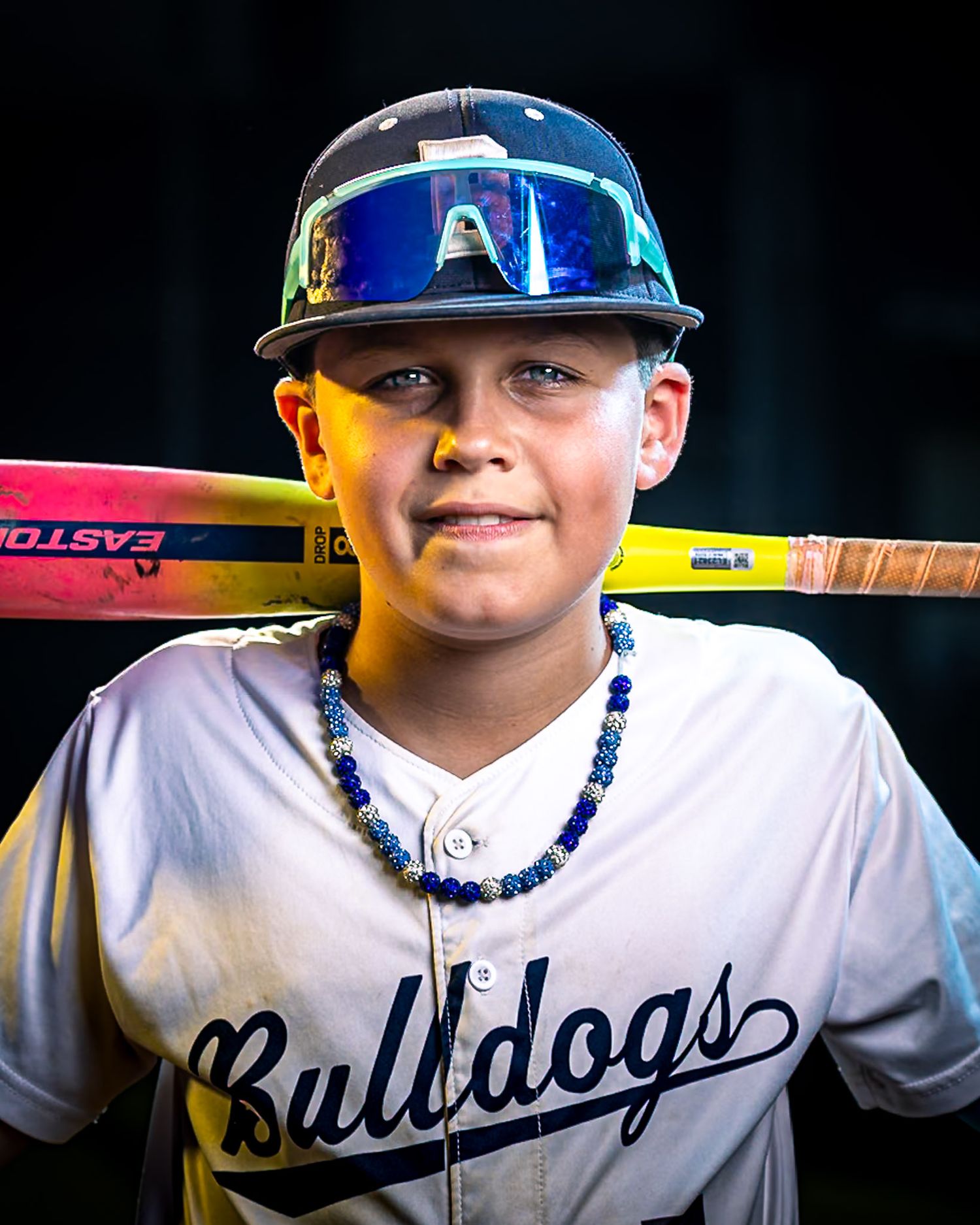 Dramatic strobe-lit youth baseball portrait of a Burke Bulldogs player with a bat by Sporty-Clips Media in Fairfax Virginia.