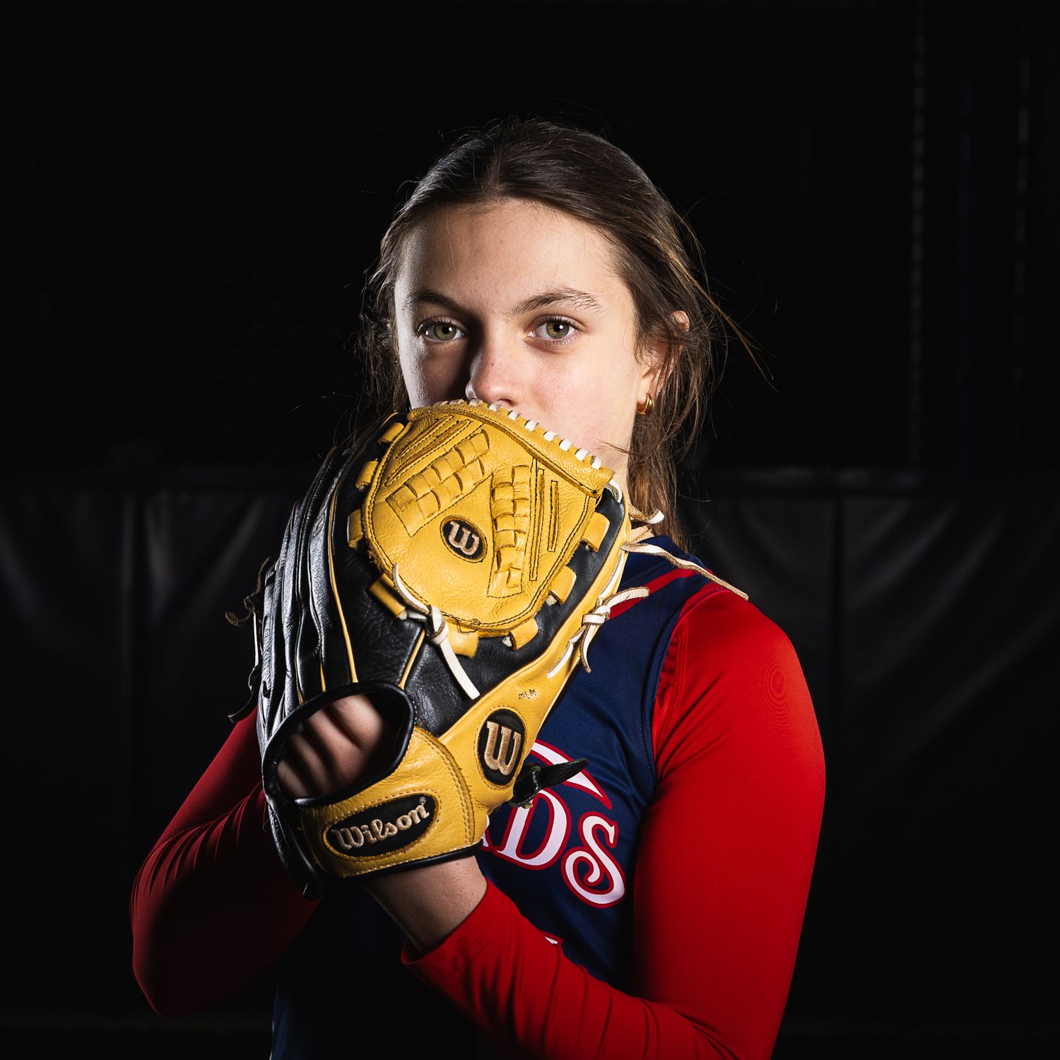 12U Firebirds softball pitcher sportrait by Sporty-Clips Media. Triple-strobe lighting on dark backdrop. Intense gaze and professional mood.