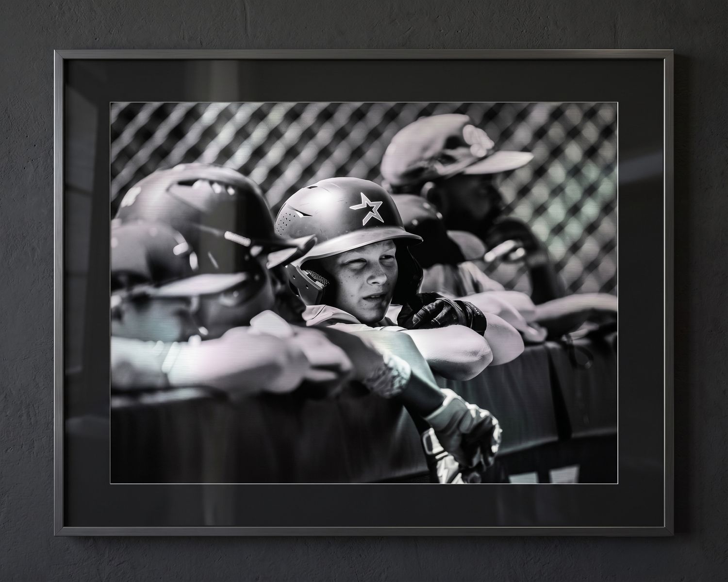 Black and white candid photo of youth baseball player watching from the dugout, professionally printed and placed in a beautiful frame.