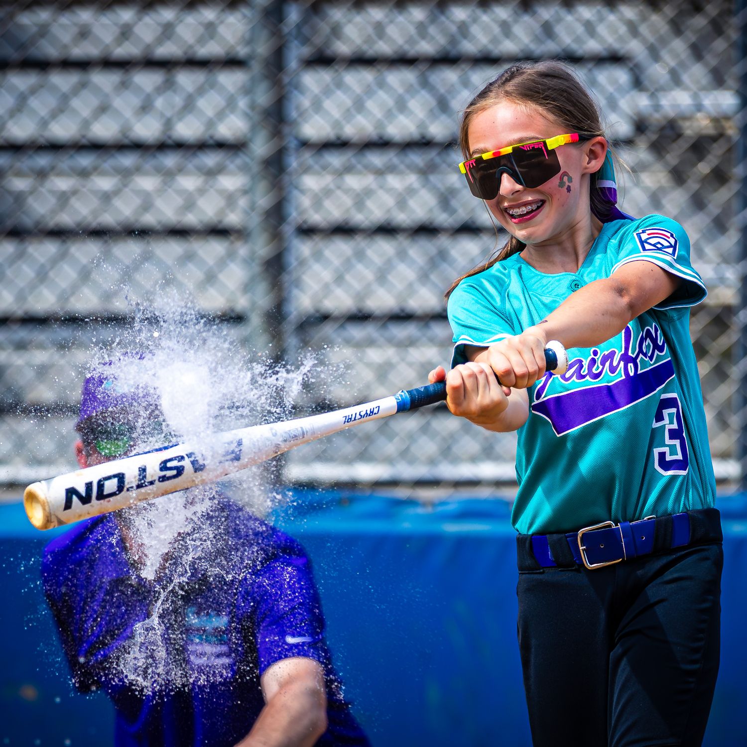 Fairfax youth softball player striking a water balloon. Premium youth sports photography in Northern Virginia by Sporty-Clips Media.
