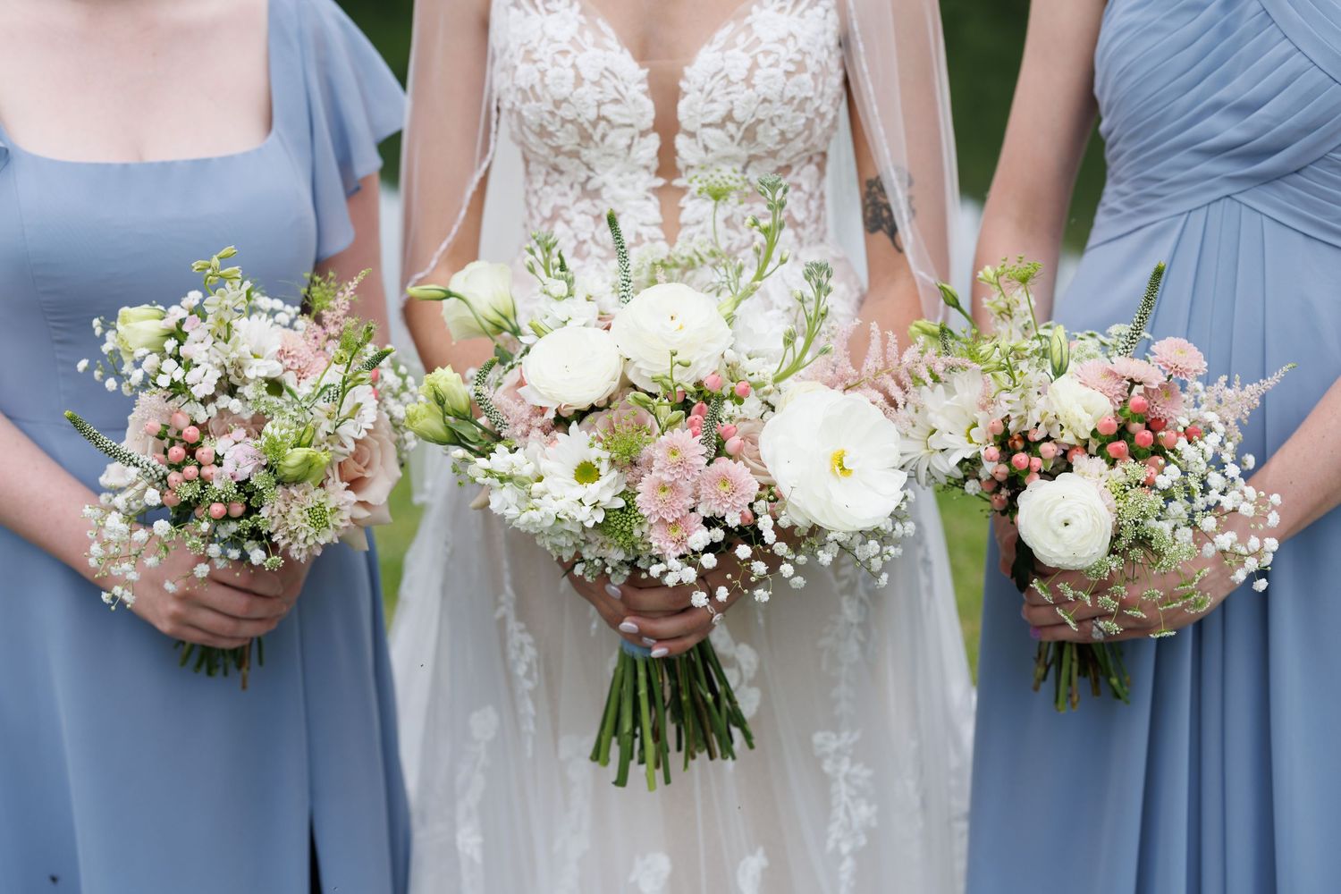 Row of wedding bouquets held by bridesmaids in light blue dresses.