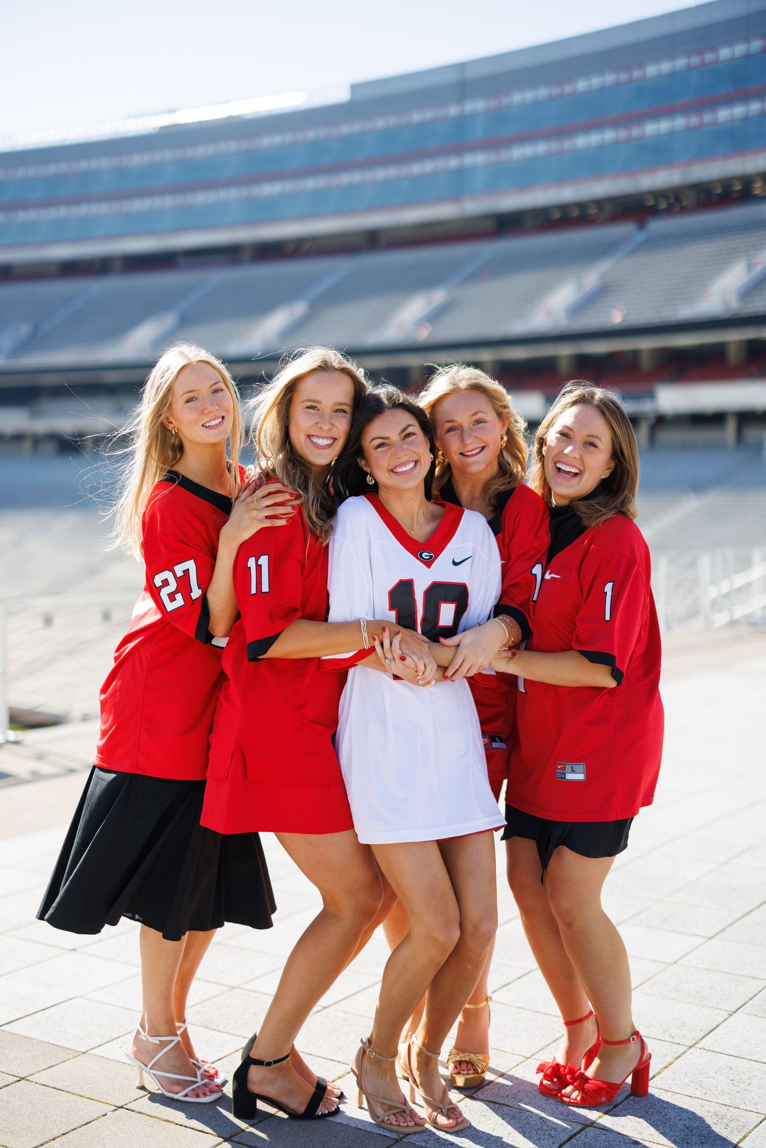 Group of cheerleaders in red and white uniforms posing together at a stadium.