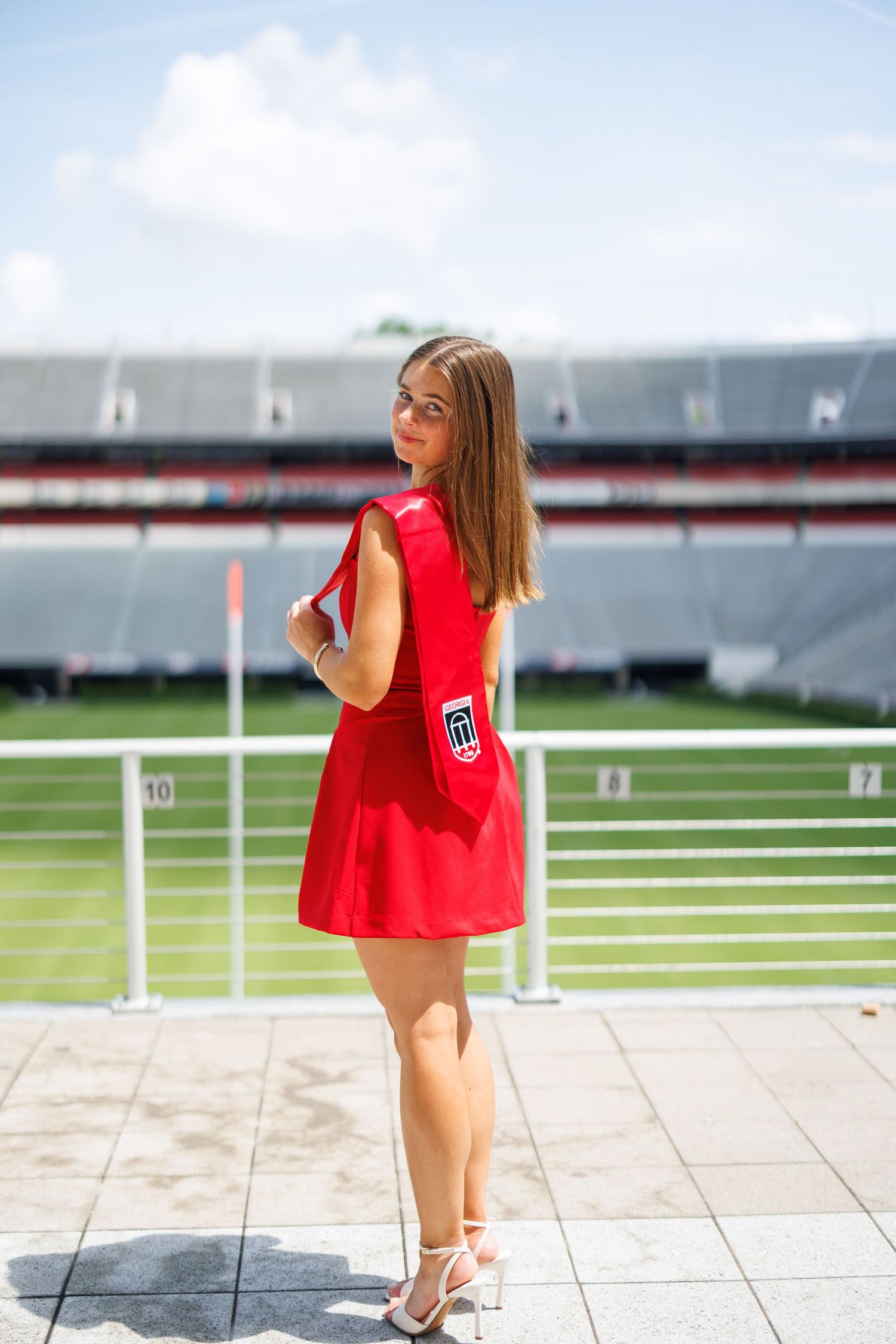 Red outfit fashion photos taken at a sports stadium with field in background.