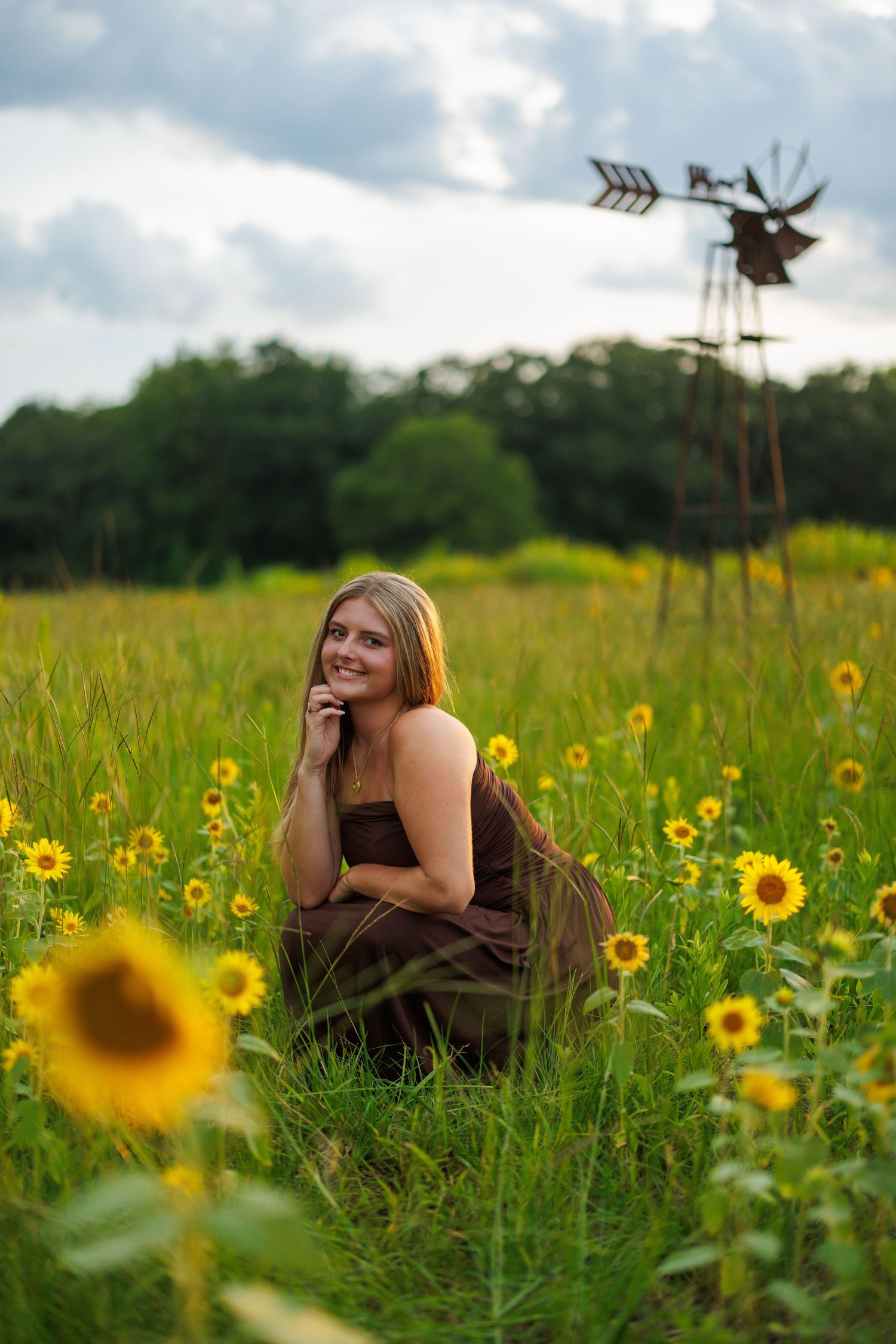 A person lies in a vibrant sunflower field on a summer day with golden flowers dotting the green landscape.