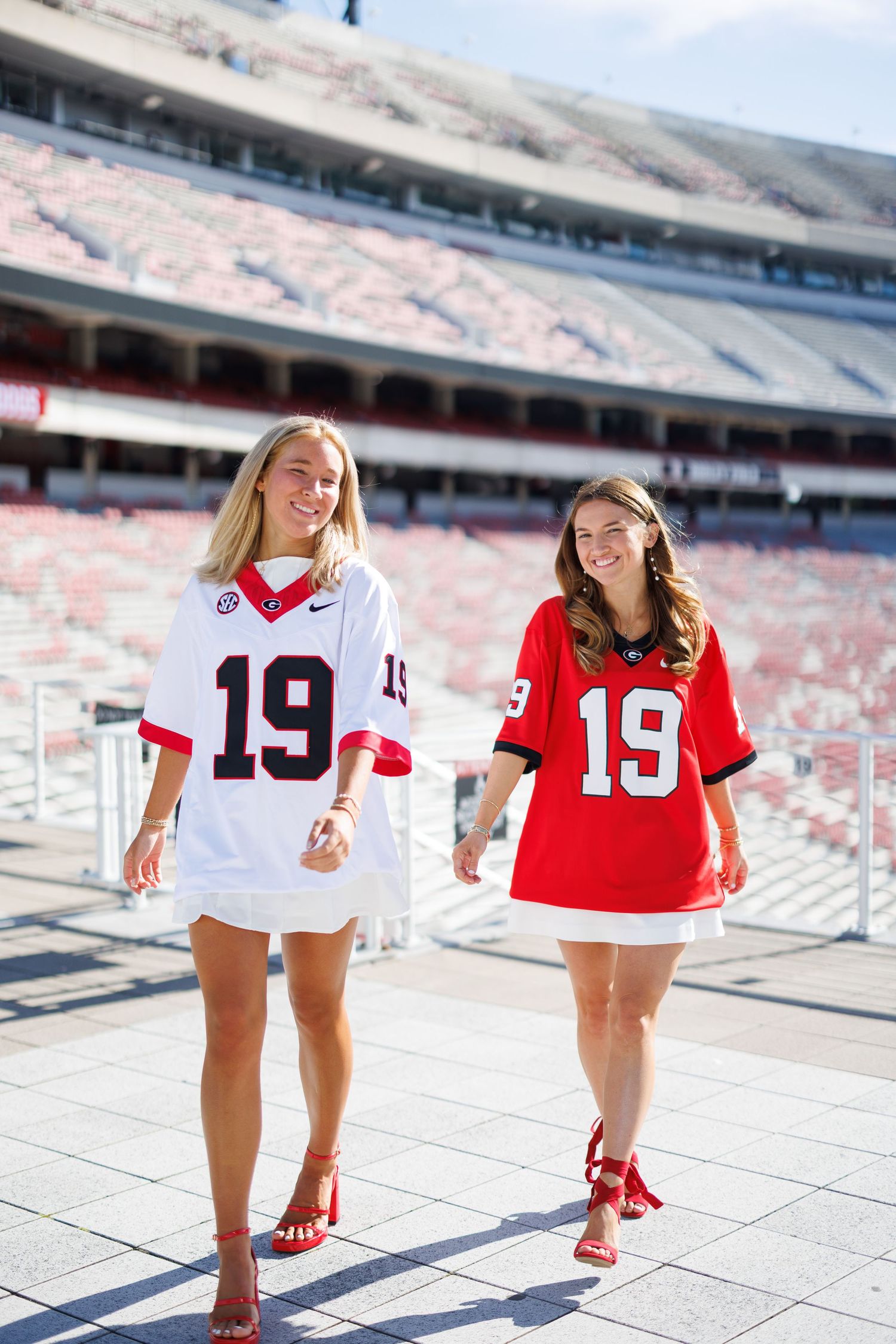 Friends in sports jerseys pose together at empty stadium steps.