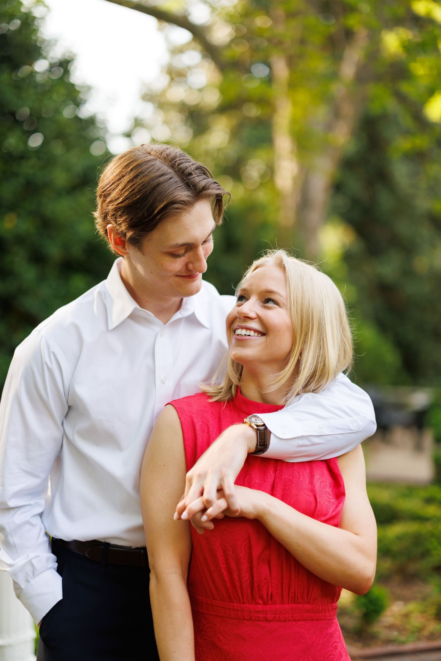 A couple shares an intimate embrace while wearing formal attire in a garden setting.