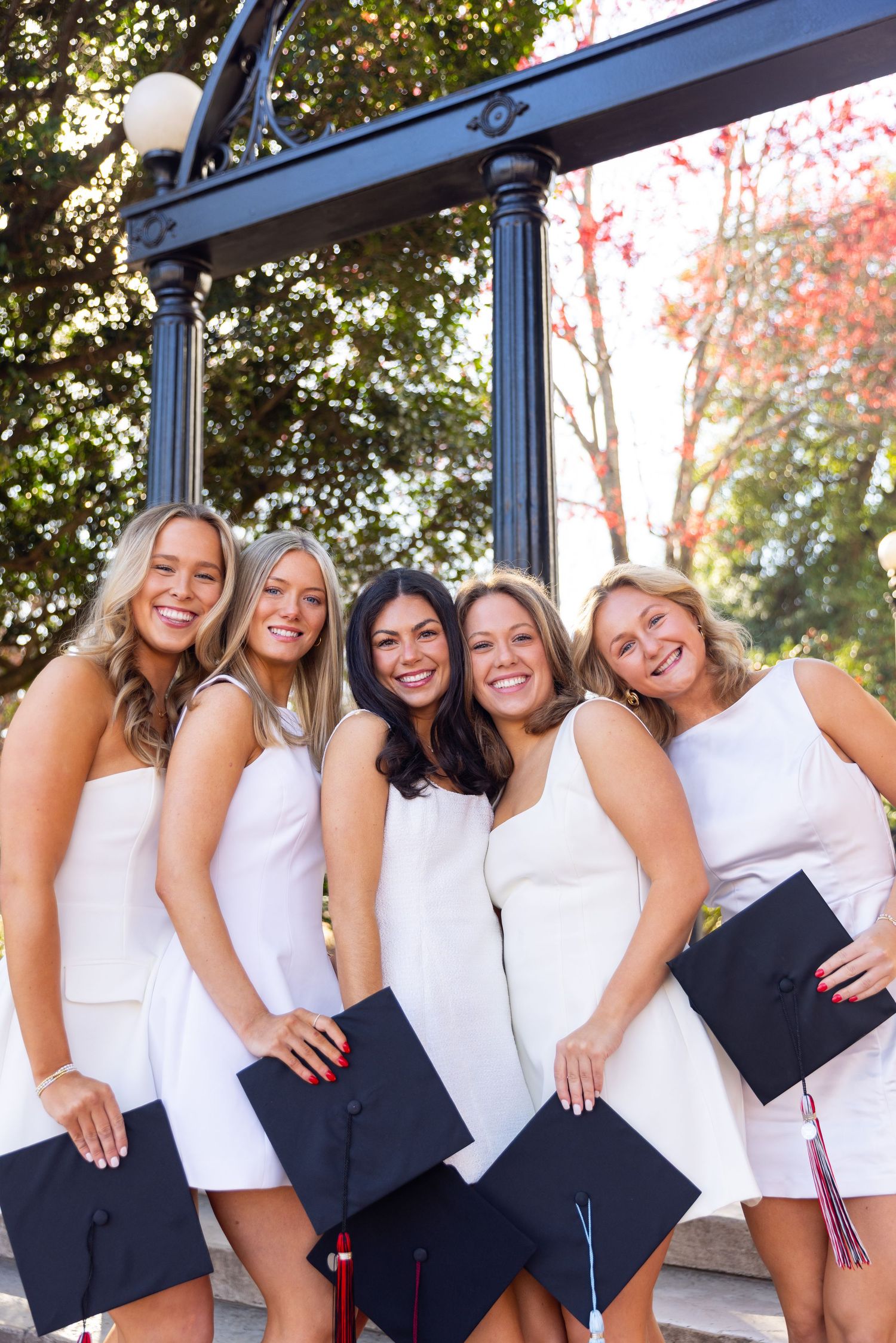 Group photo of friends in matching white tops and dark bottoms posing together outdoors.