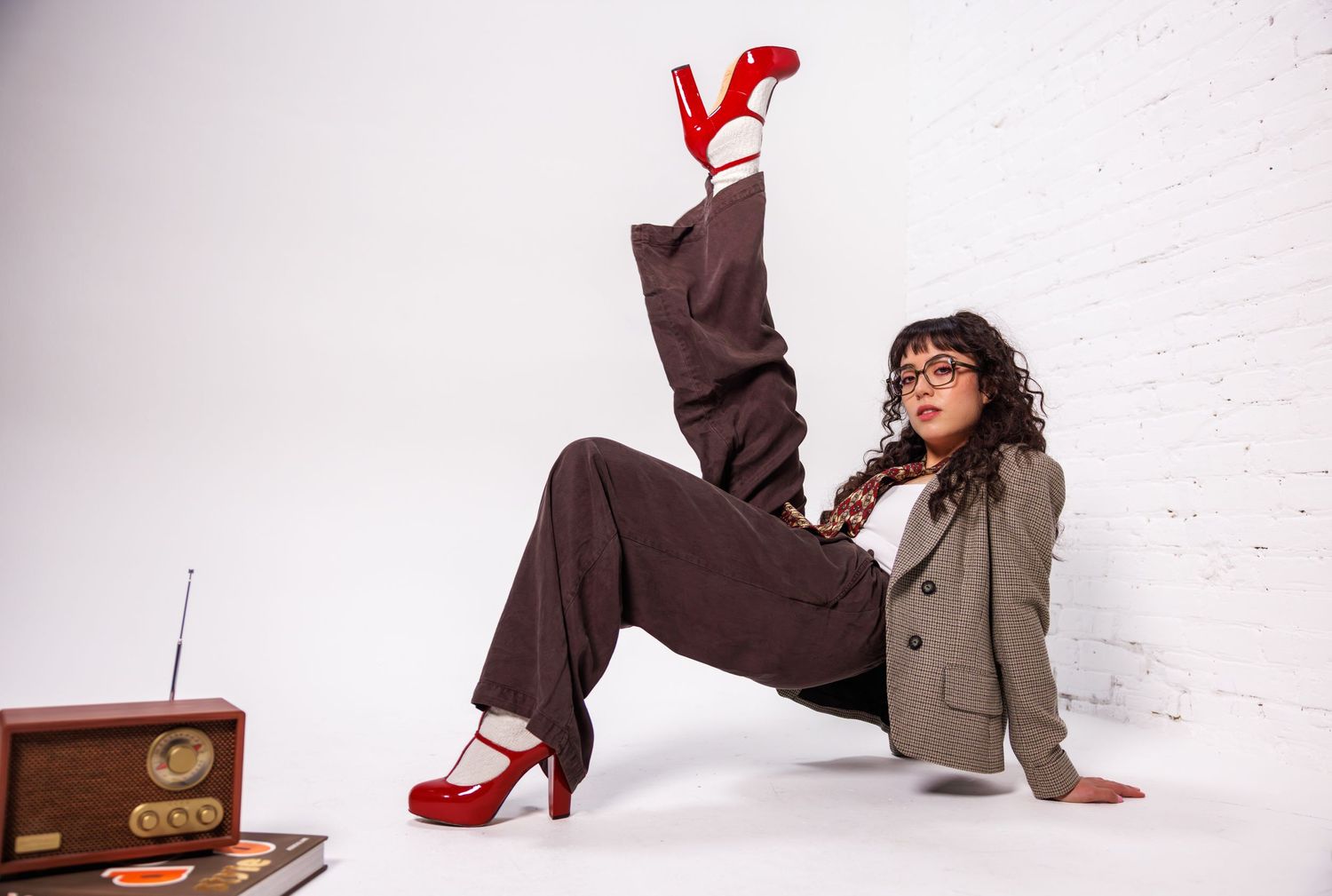 Creative fashion poses with red shoes and vintage radio against white studio background.