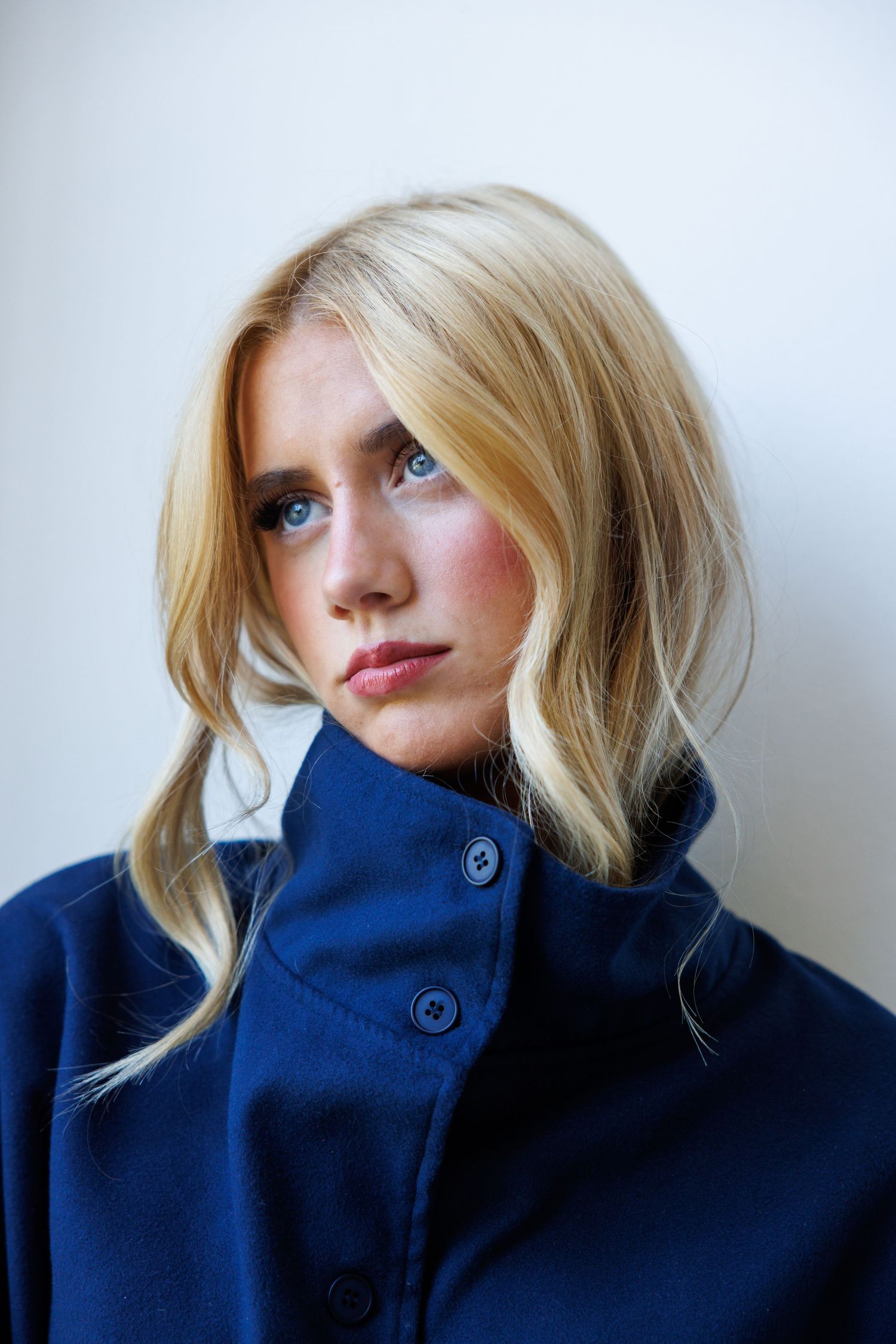 A series of five artistic portrait shots showing a person in a navy turtleneck sweater against a white background.